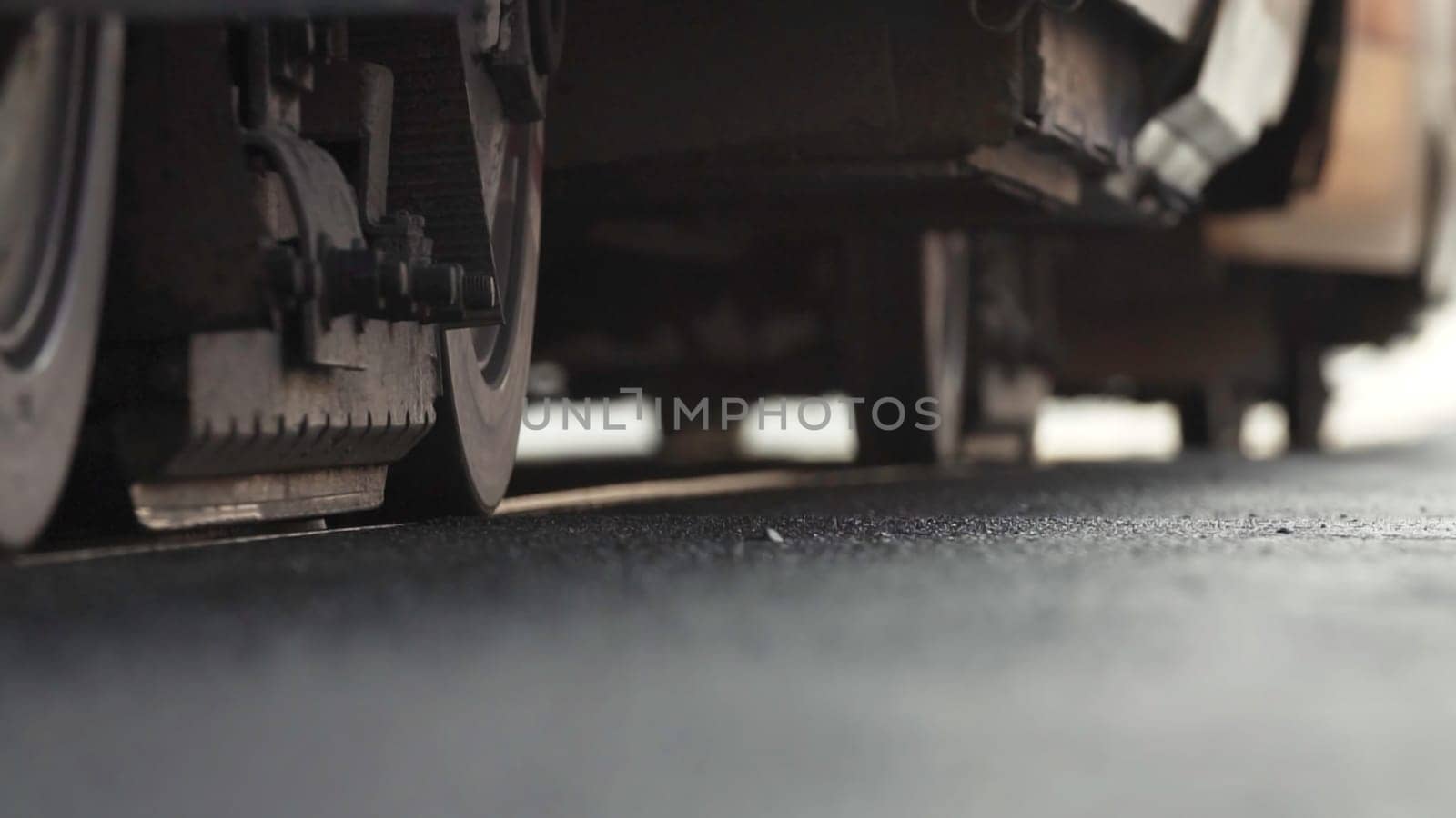 A detailed view showcasing the industrial vehicle wheels positioned on a freshly paved and smooth asphalt surface. Stock Clip