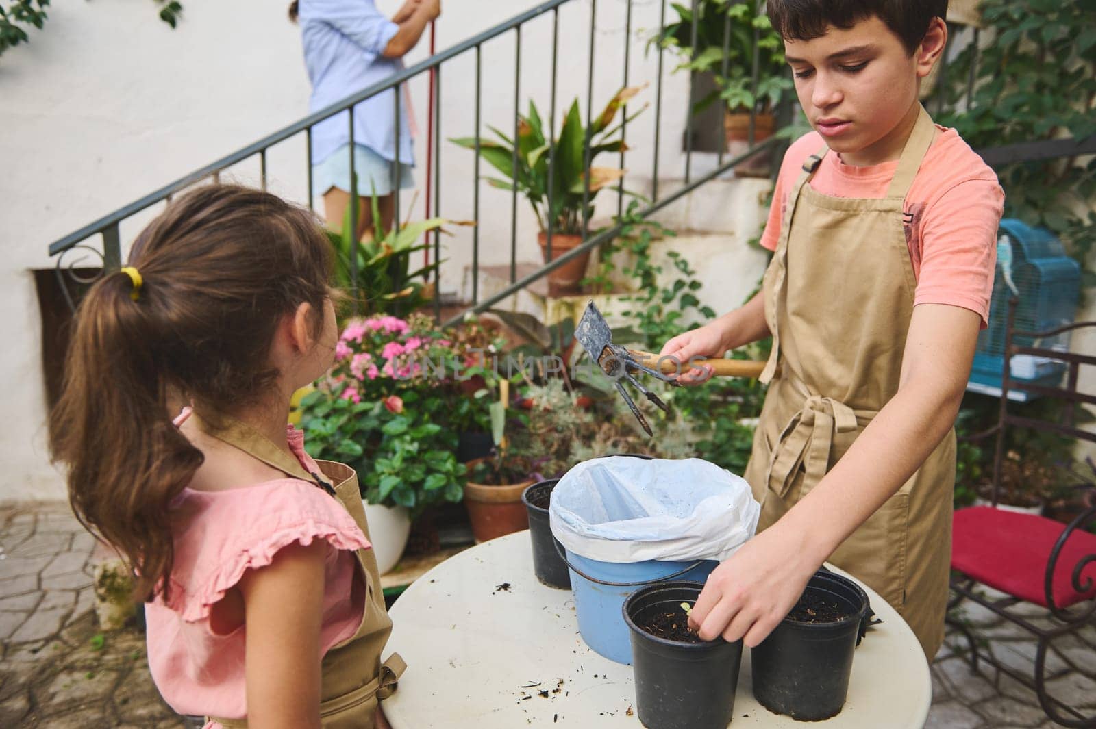 Two children engage in gardening, planting in pots on a sunny day. A sense of teamwork, nature, and learning permeates the scene as they enjoy outdoor activities.