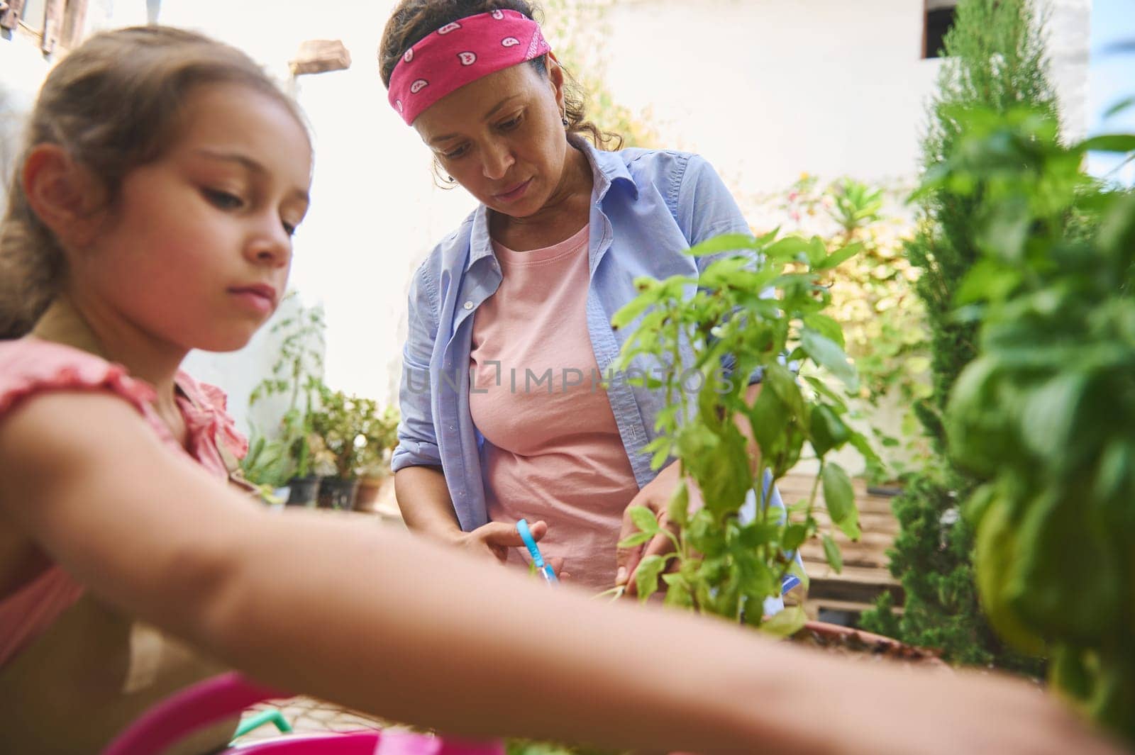 A mother and daughter enjoy gardening in their backyard garden, tending to plants with care. The outdoor setting and vibrant greenery create a peaceful and bonding atmosphere.