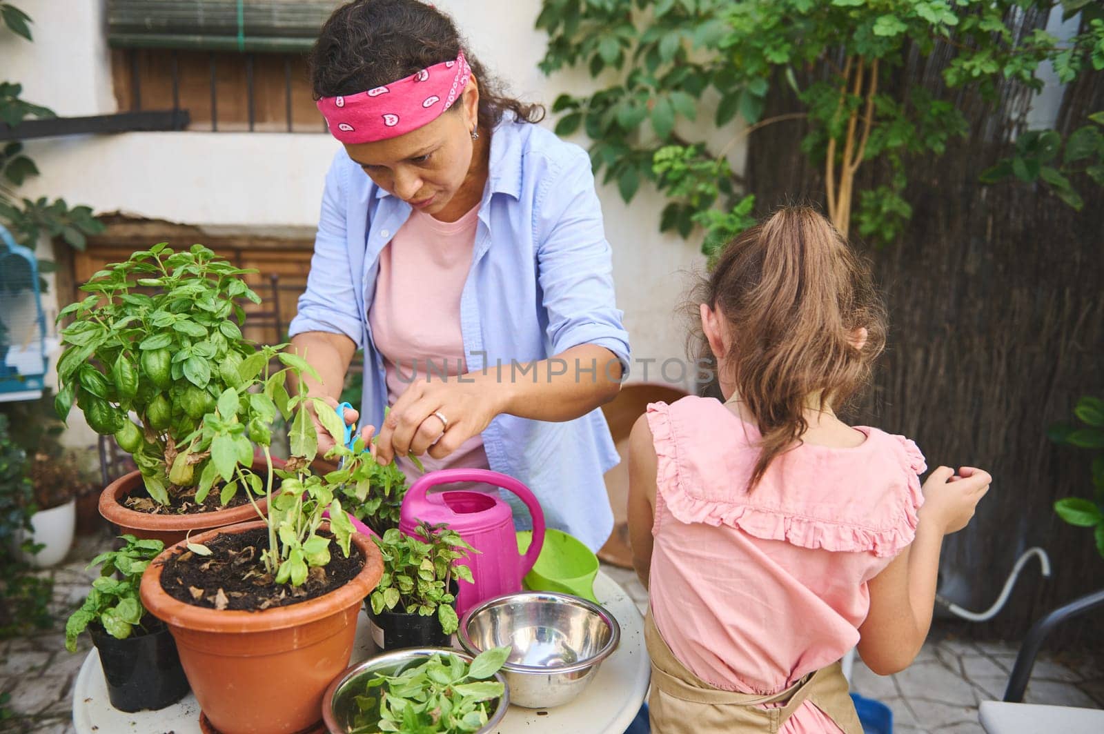 A mother and daughter spend quality time together gardening in their backyard, surrounded by plants and greenery. They share a love for nature and nurturing plants.