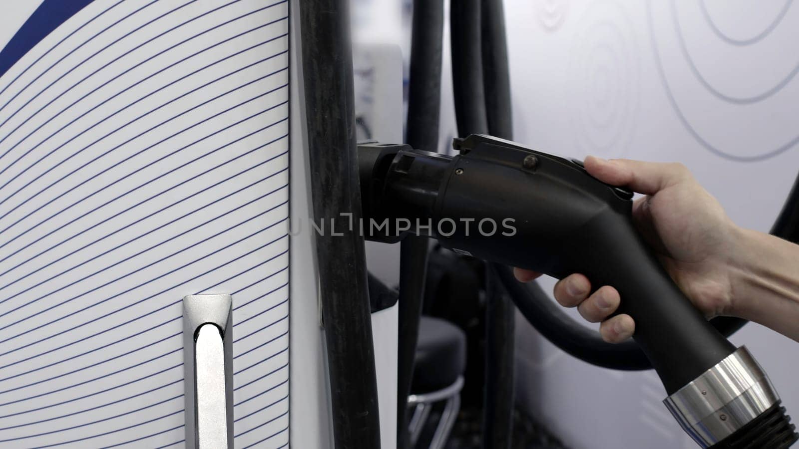 A detailed perspective showcasing the electric vehicle charging equipment along with associated cables. Media