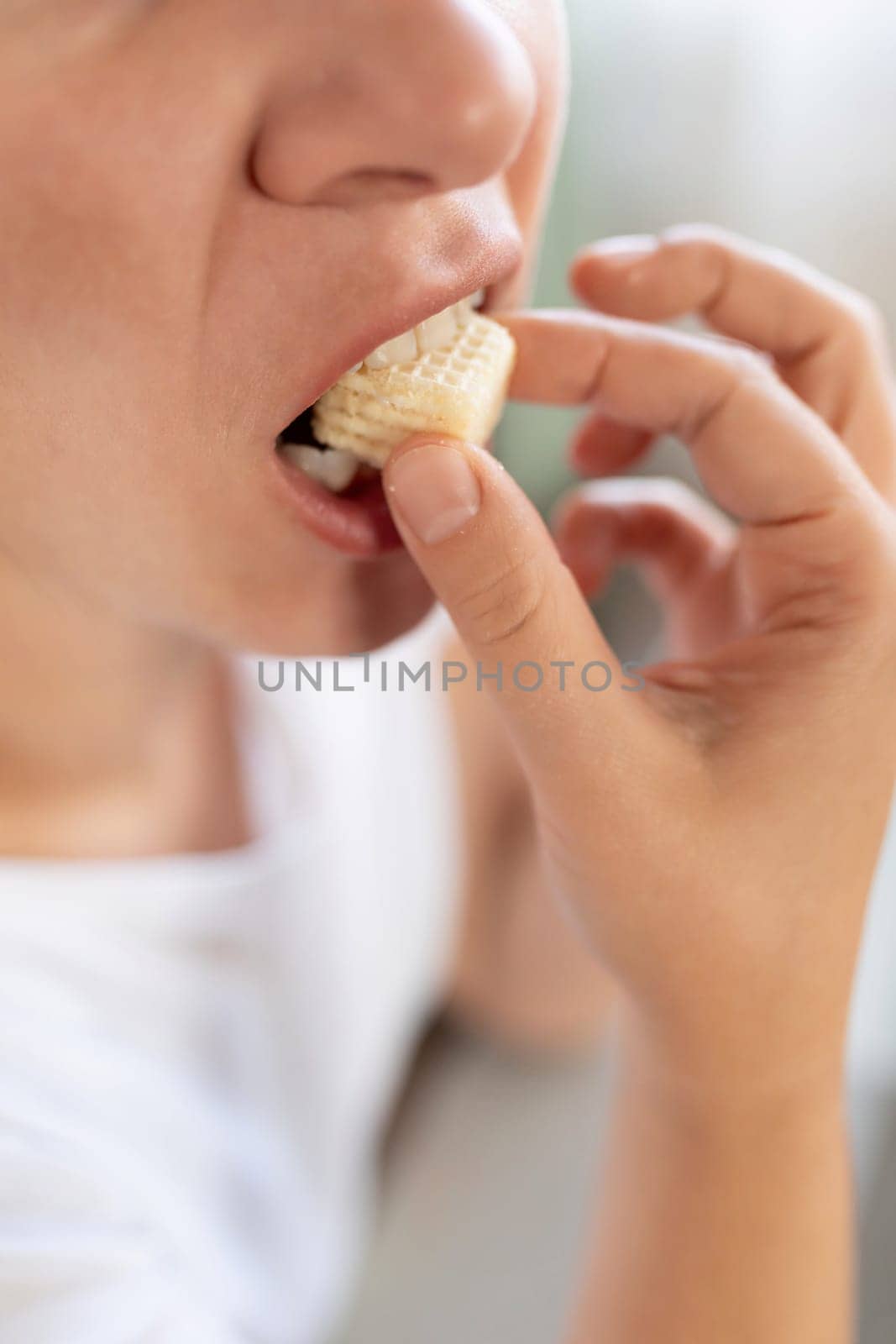 young woman snacking on sweet junk food with trans fats by TRMK