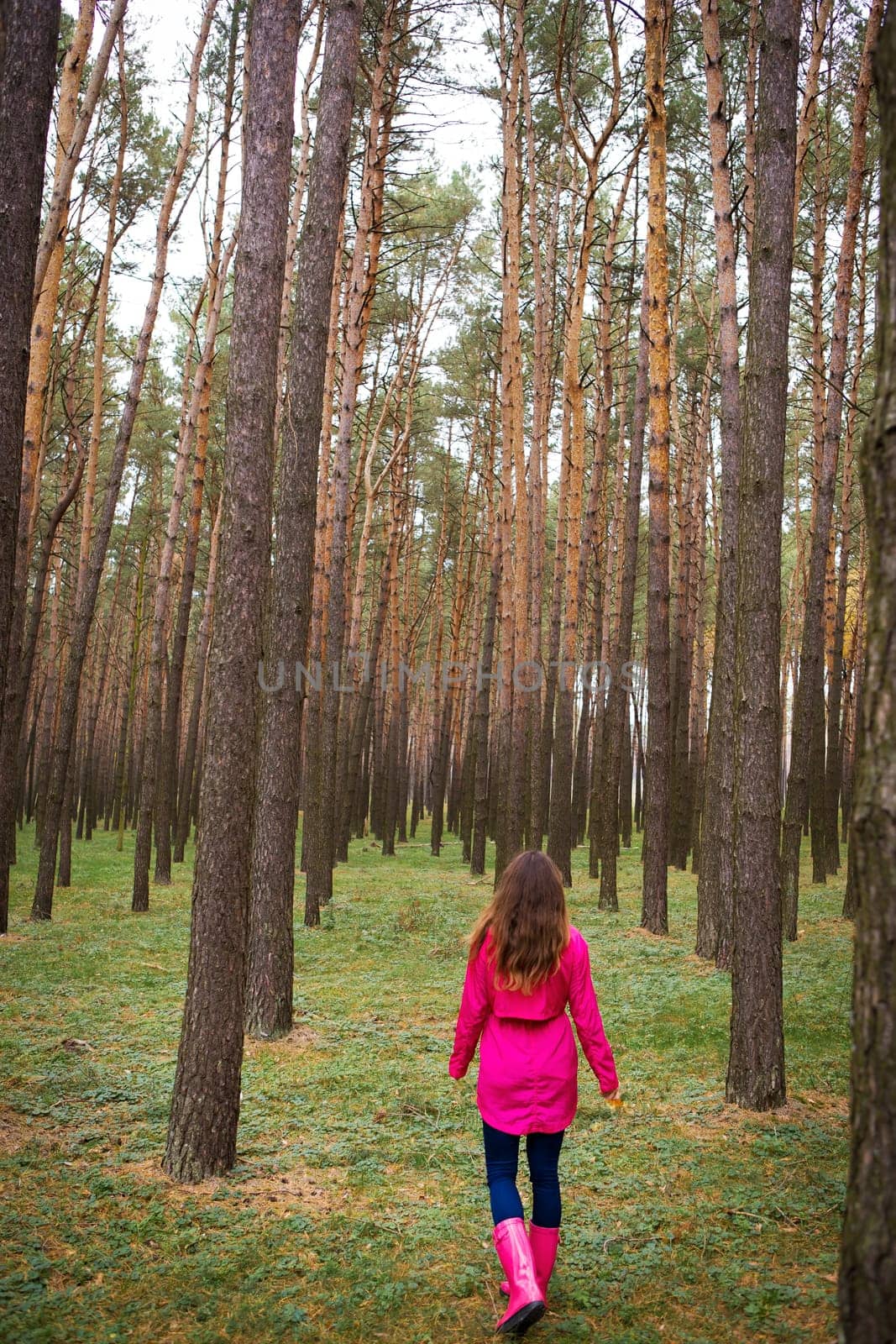 girl in a raincoat and rubber boots walking alone in the woods by sfinks