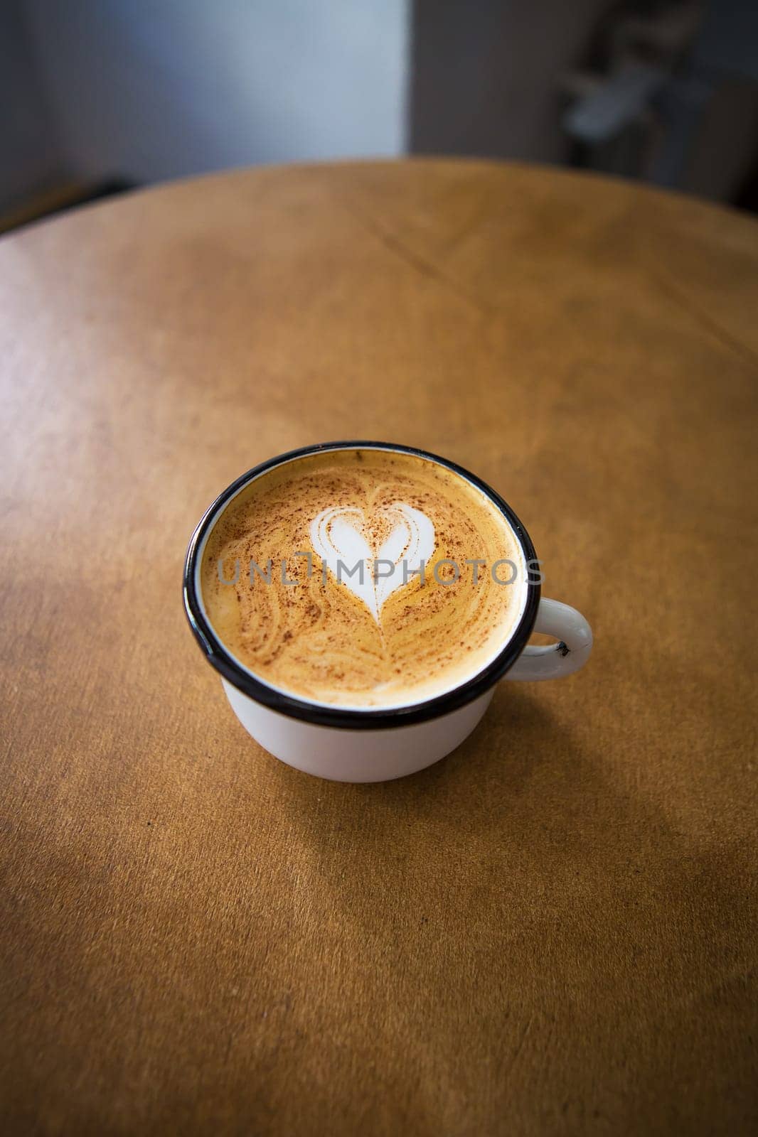 cup of cappuccino with a heart shaped pattern on a wooden table.