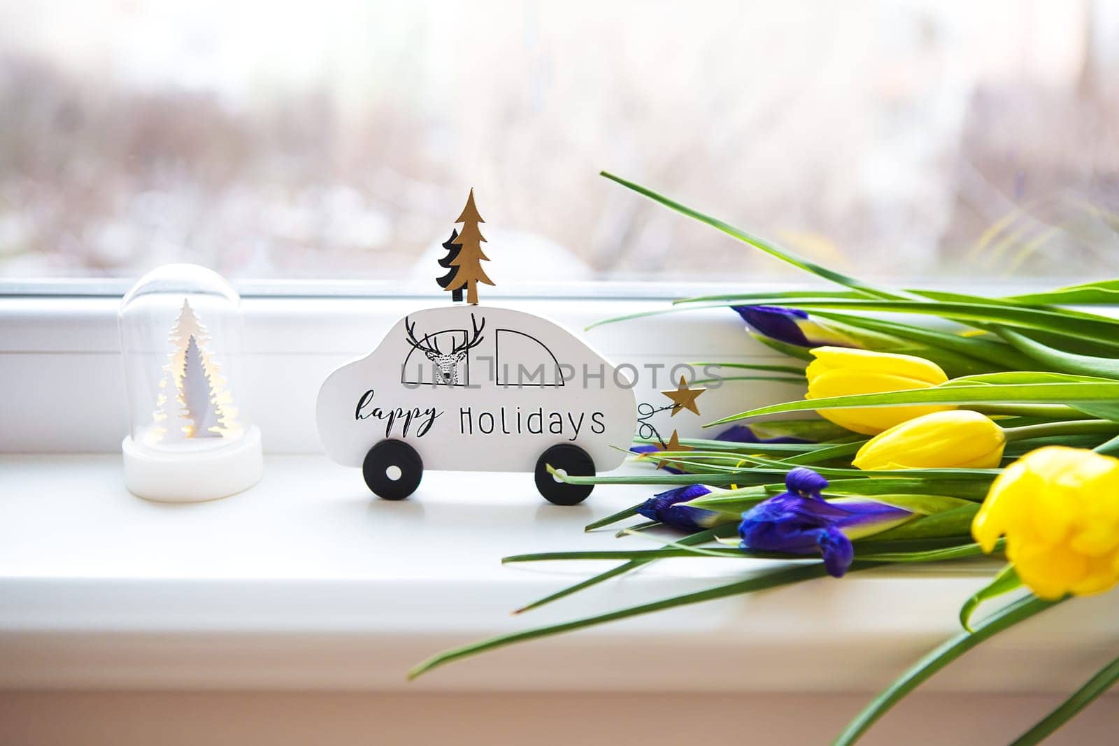 beautiful flowers-tulips and irises lie on the windowsill with a typewriter and a Christmas tree.