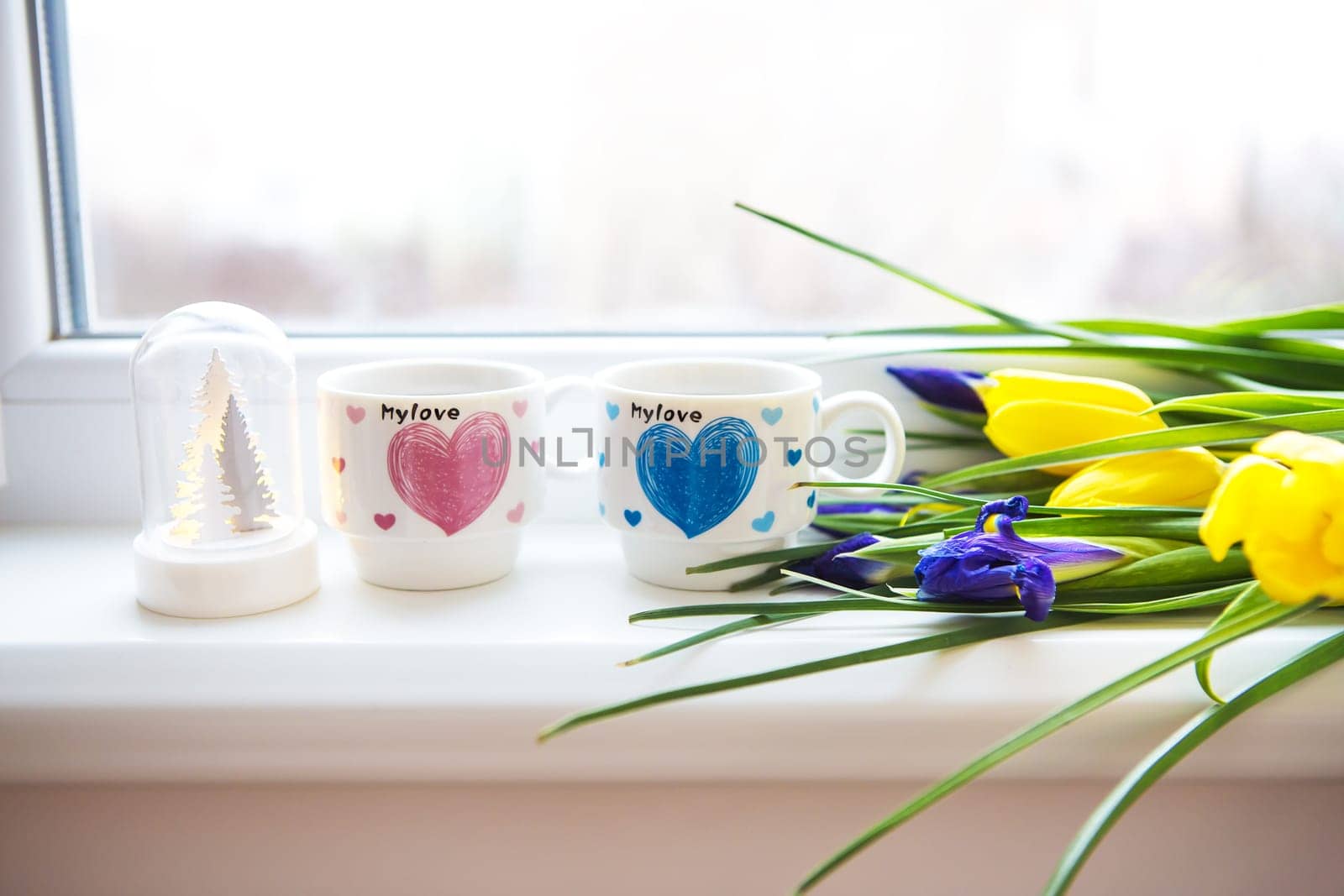 beautiful flowers-tulips and irises lie on the windowsill with two cups of coffee.
