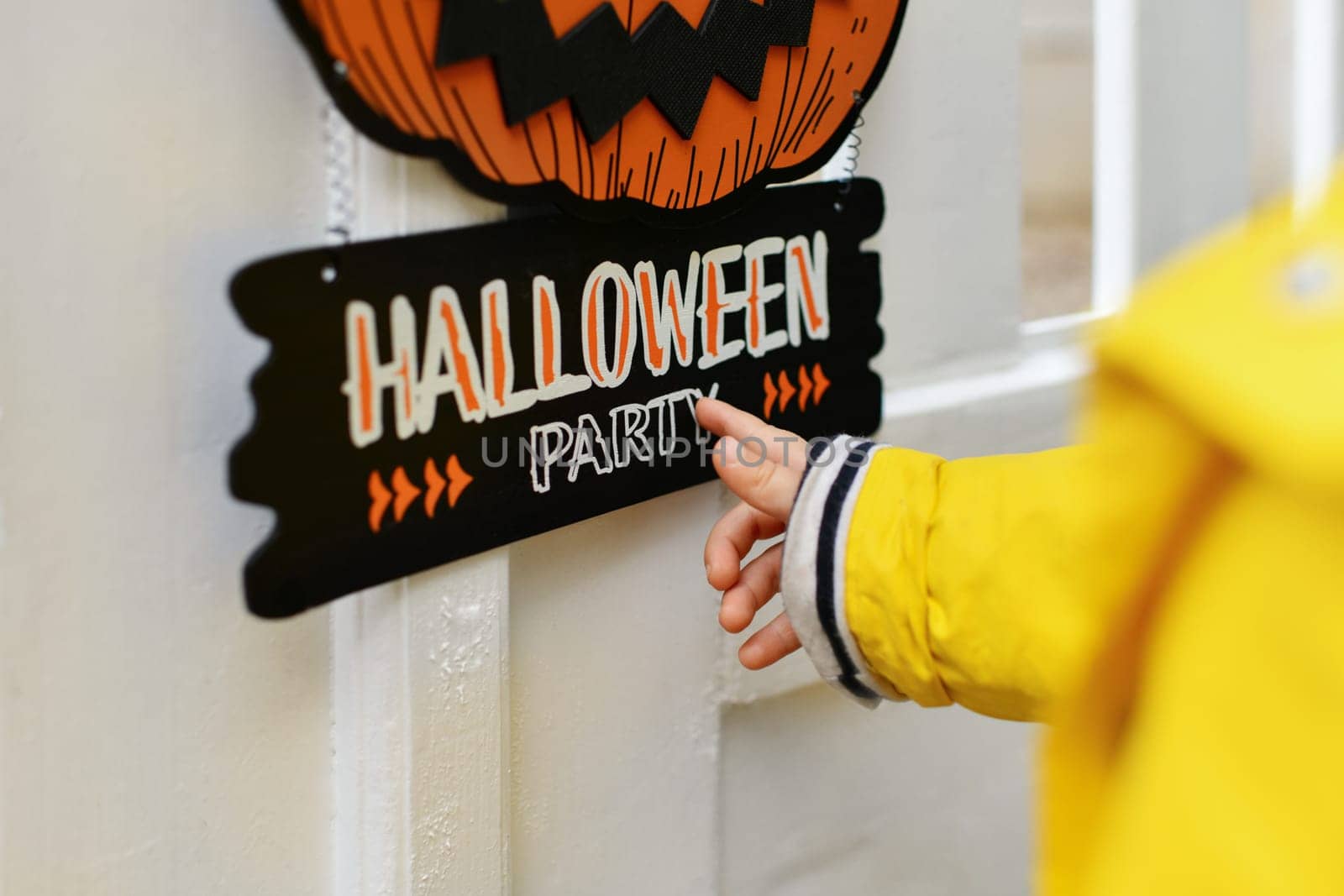 A kid with Carved pumpkin on the fence of the house