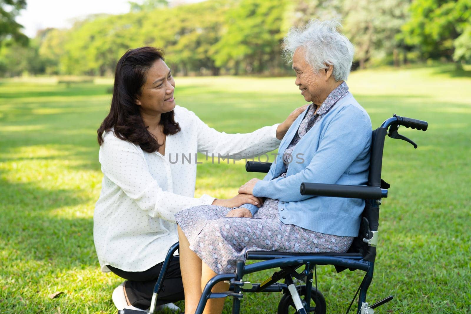 Caregiver help and care Asian elderly woman use walker with strong health while walking at park in happy fresh holiday.