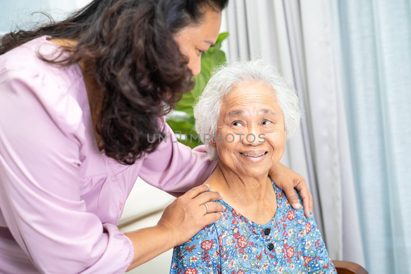 Caregiver help and support Asian senior woman with love and care in home.