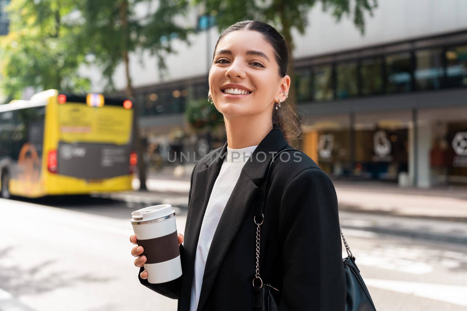 Ready for the day. Cheerful multiracial businesswoman in city street holding a thermo mug.
