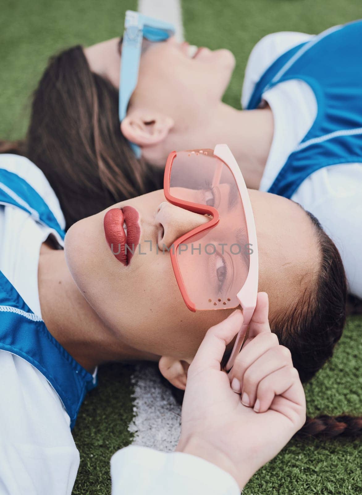 Women, portrait and athlete with fashion sunglasses for edgy styling, cosmetics and makeup in trendy eyewear. Athletes, sports field and sportswear on ground, teammates and cool posing with friend.