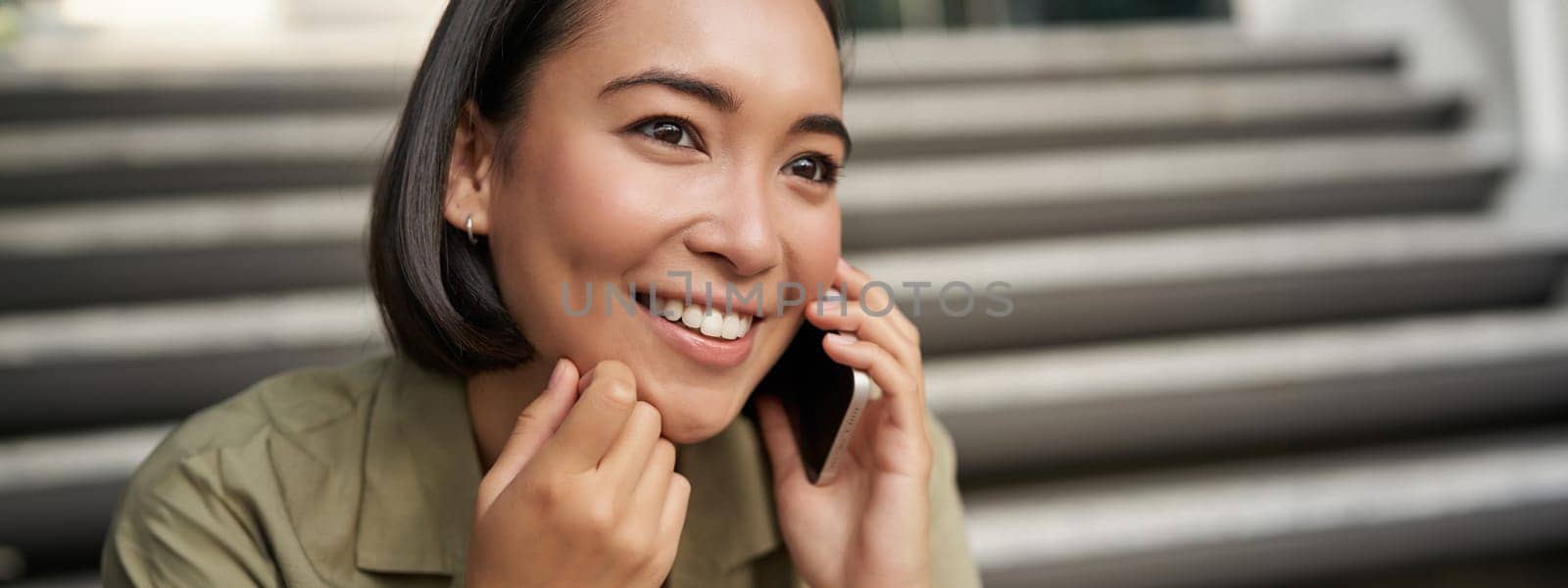 Close up portrait of asian girl talks on mobile phone. Young woman having a phone call, using her telephone.