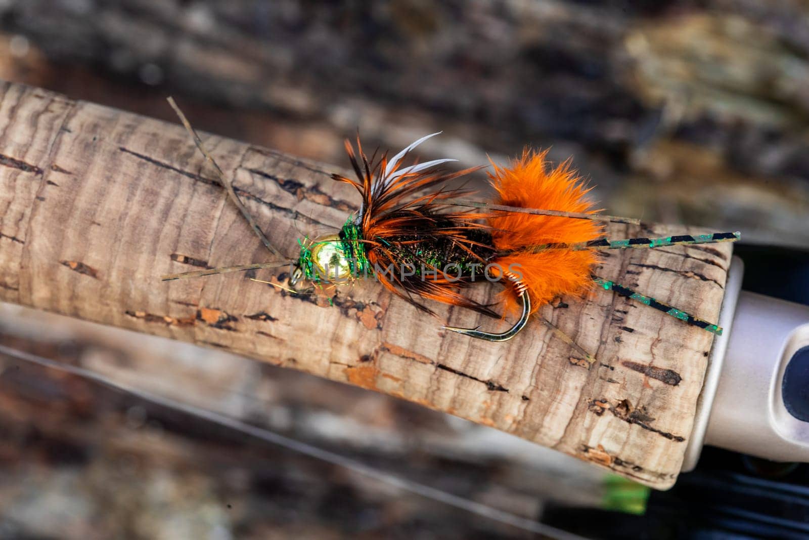 Wet fly nymph fishing pattern at a river in Oregon set on the cork handle of a rod.