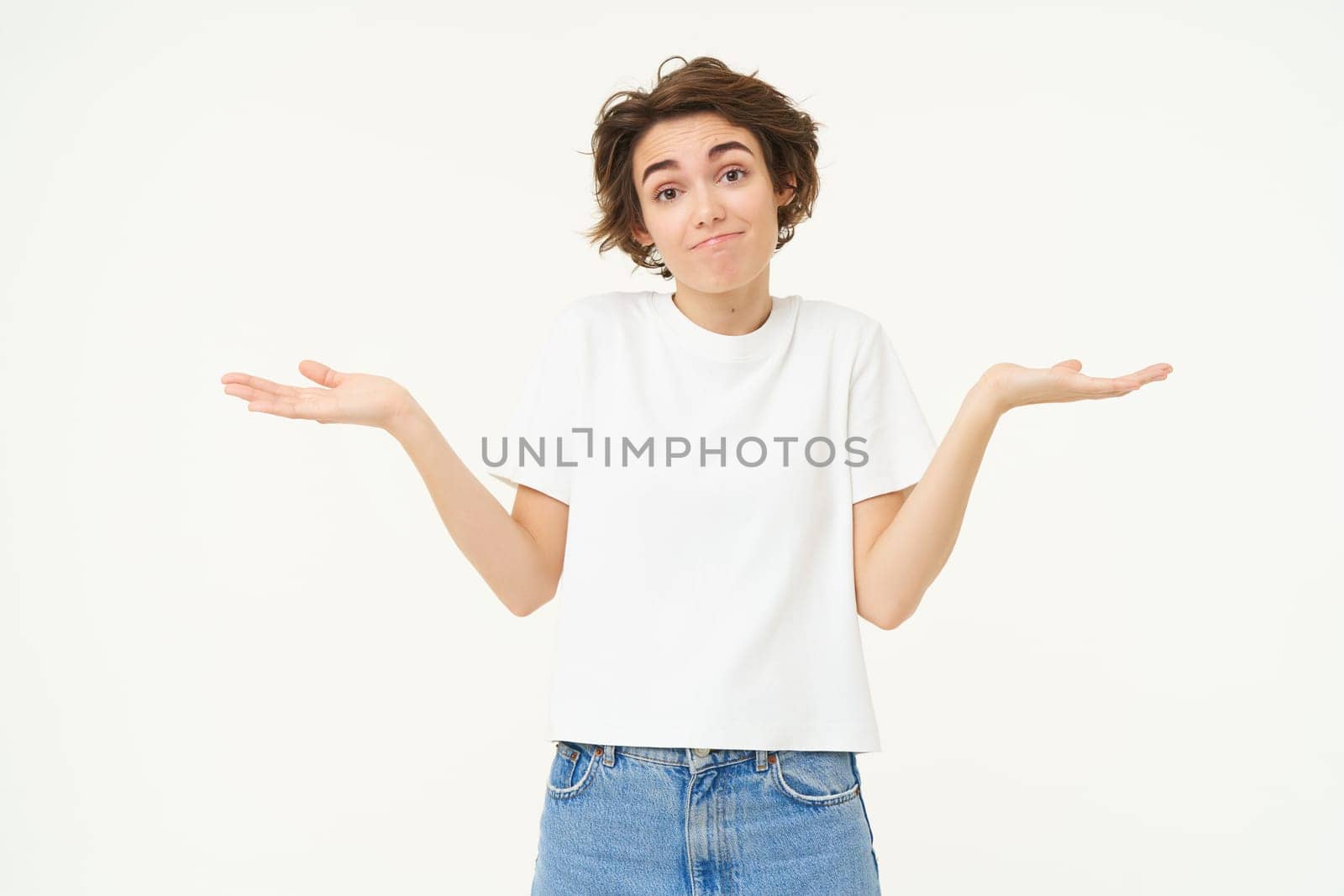 Woman shrugs her shoulders, looks clueless, doesnt know anything, stands confused against white background.