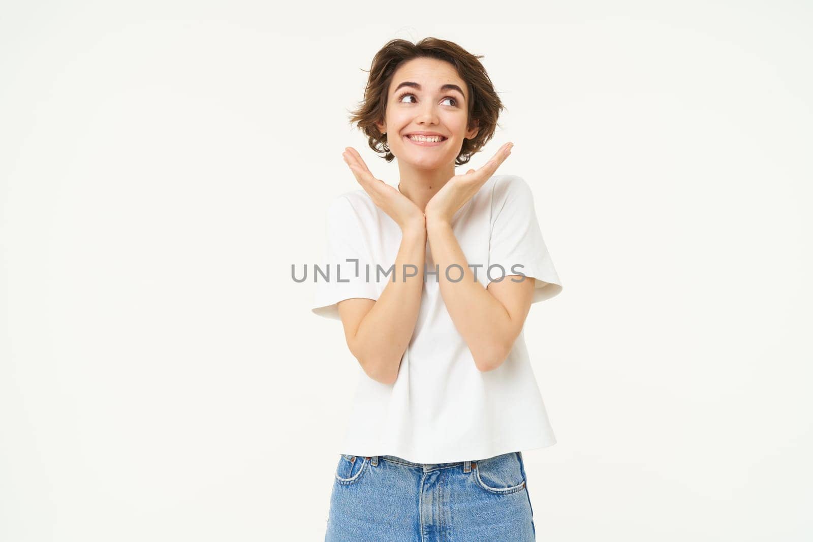 Portrait of woman making cute pose, gazing with admiration and love, posing over white background. People and lifestyle concept