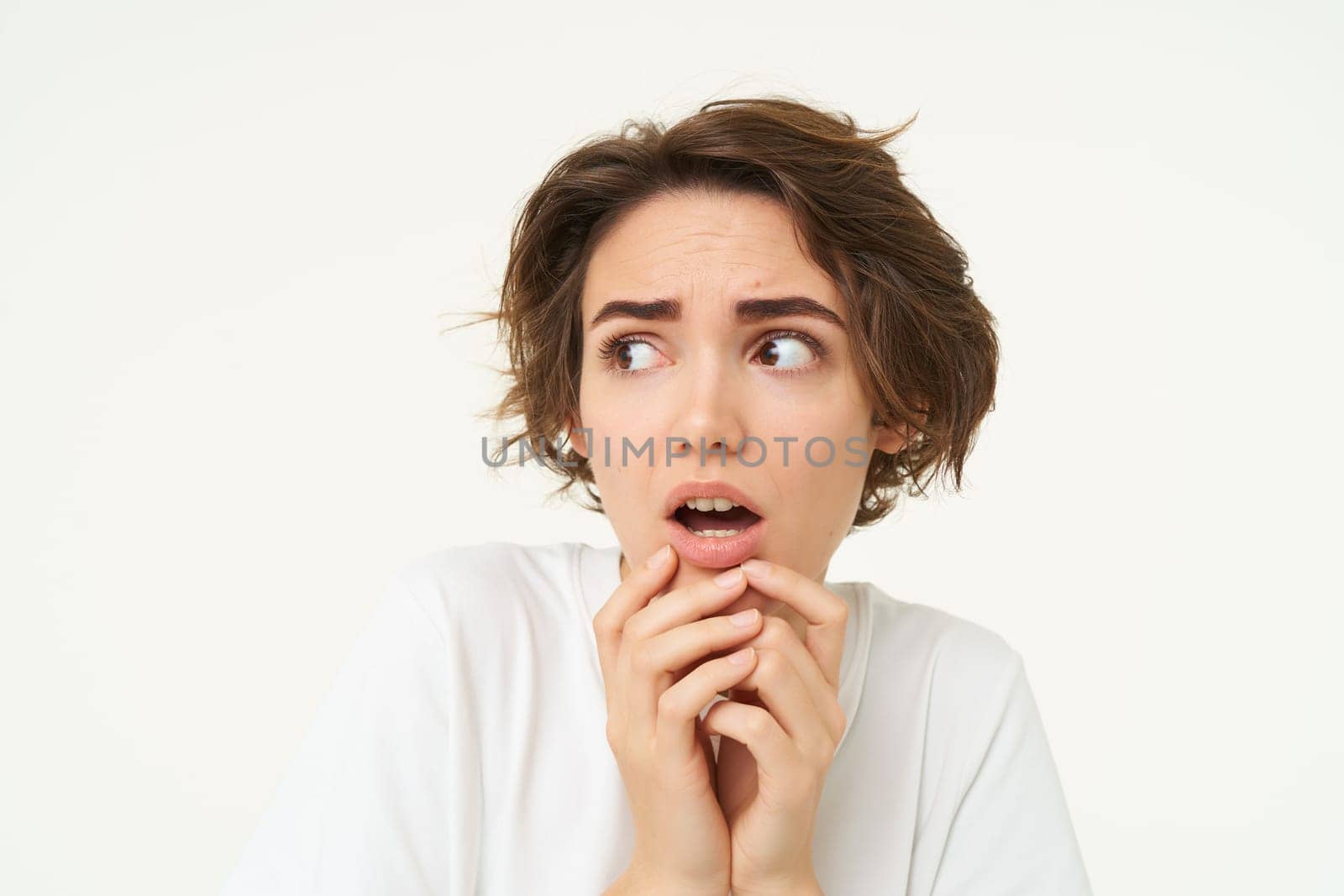 Close up of shocked, scared and worried young woman, trembling from fear, posing over white background.