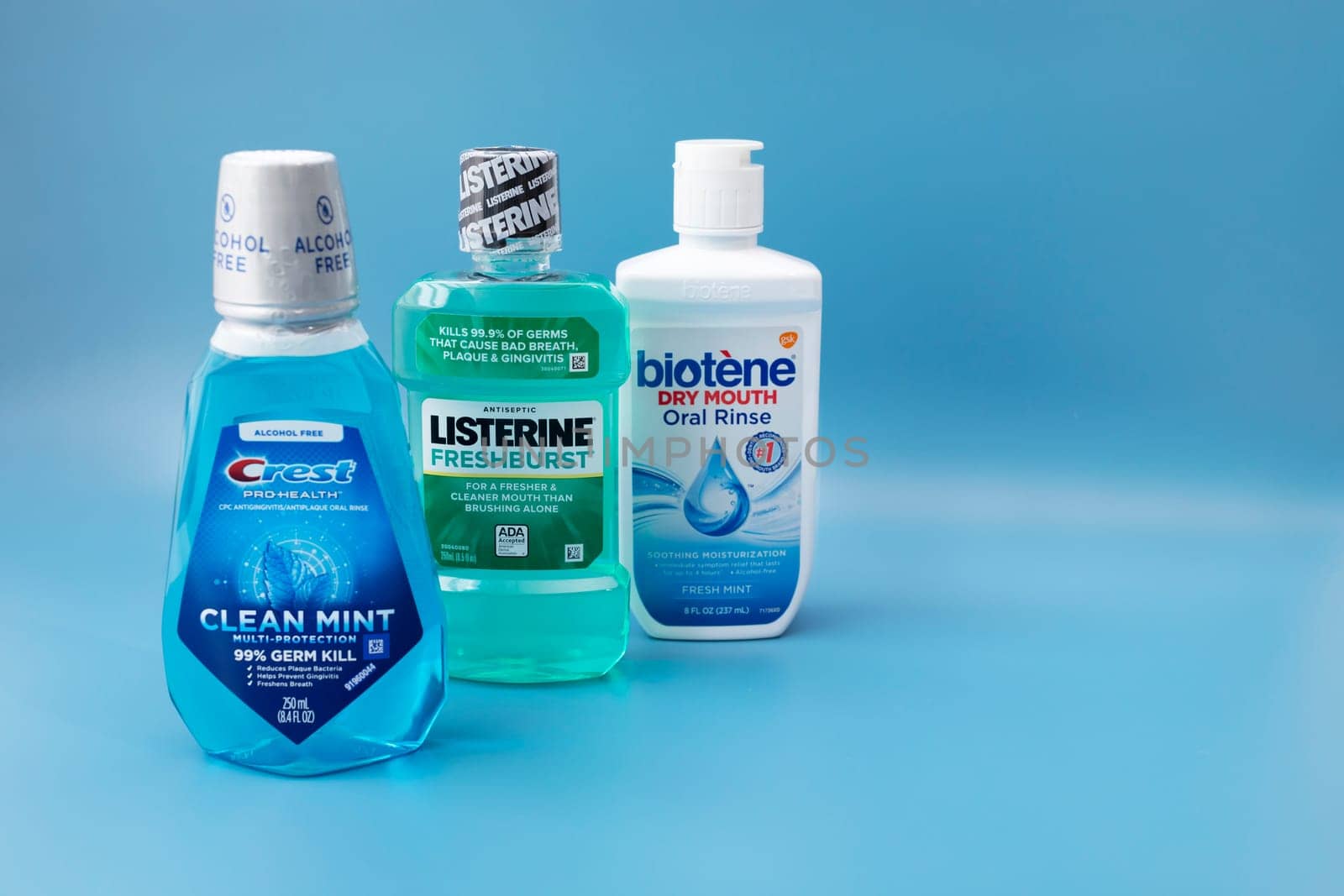 Few Mouth rinse or Mouthwash Bottles 'Crest', 'Listerine', 'Biotene' on Blue Background. Space For Text. Liquid for Rinsing Mouth. Oralcare Product. Horizontal Plane. Phoenix,USA: 09.24.2023.