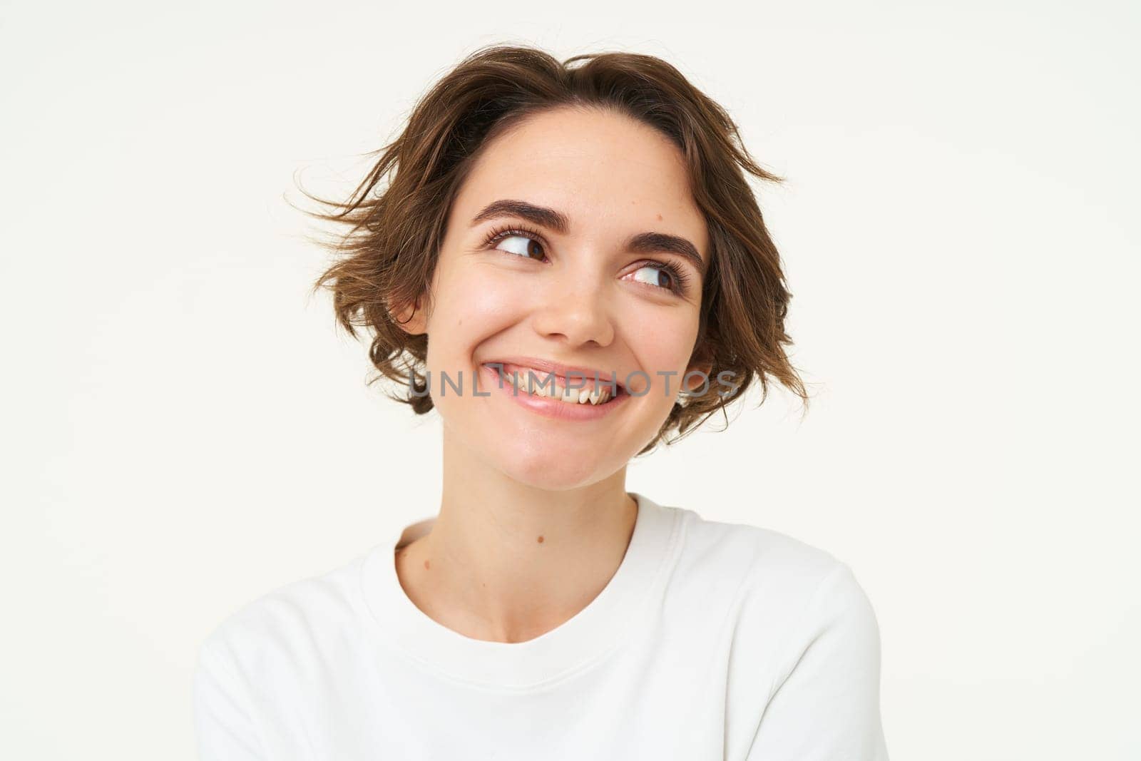 Close up portrait of brunette girl with short haircut, smiling and looking happy, posing over white background.