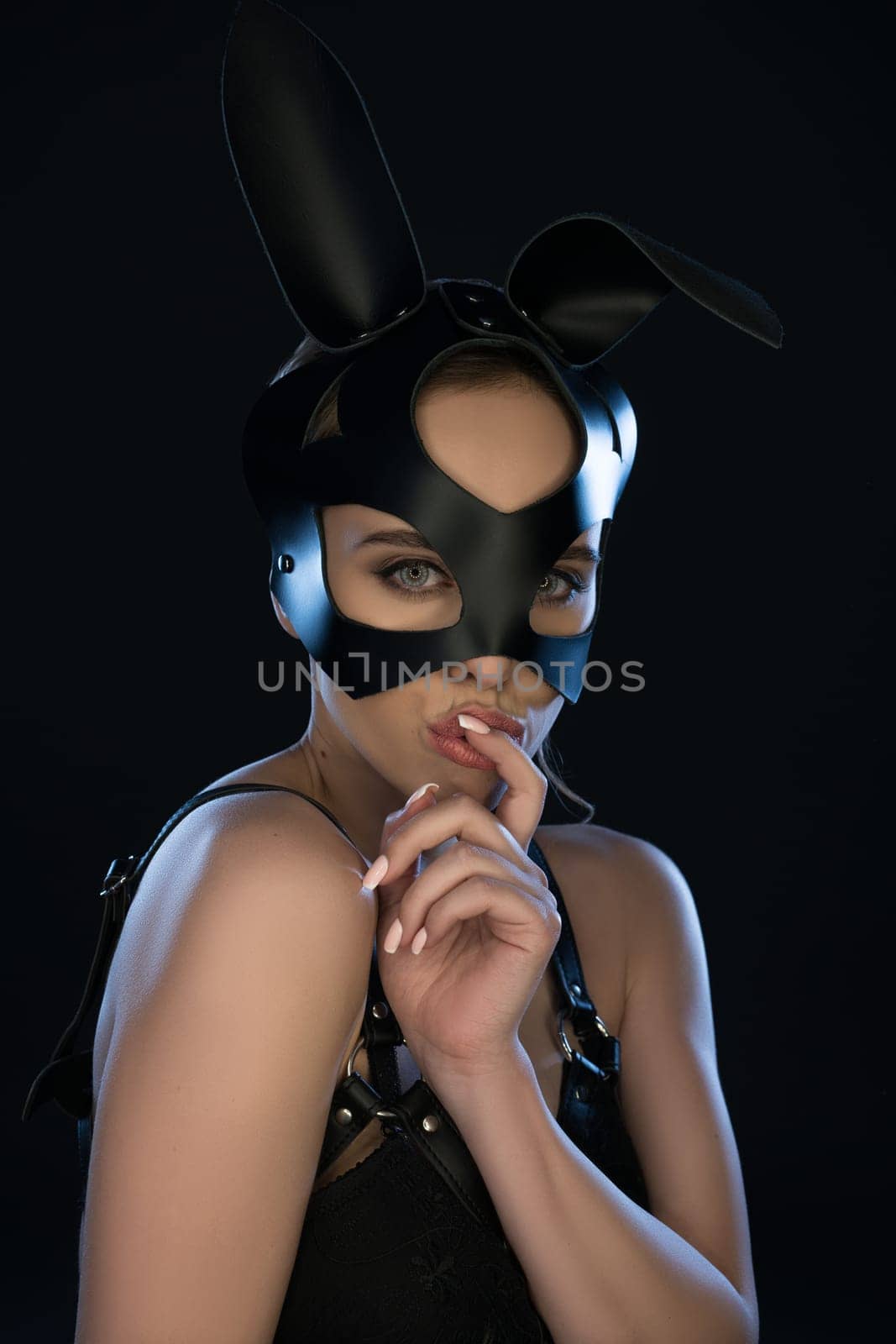 Sexy woman in black leather rabbit mask waist up portrait