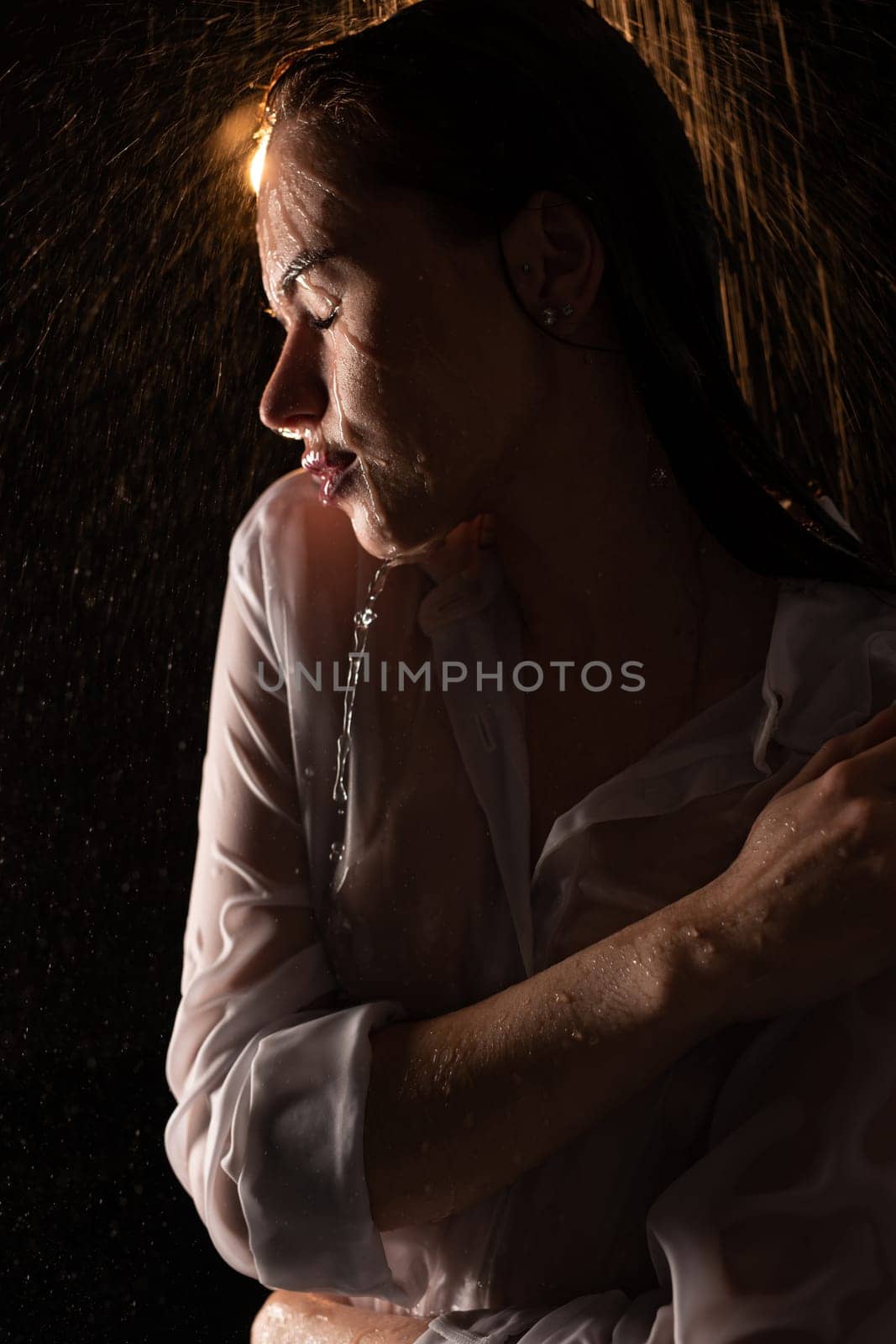Sexy young woman wearing white shirt shot in shower profile portrait in the dark
