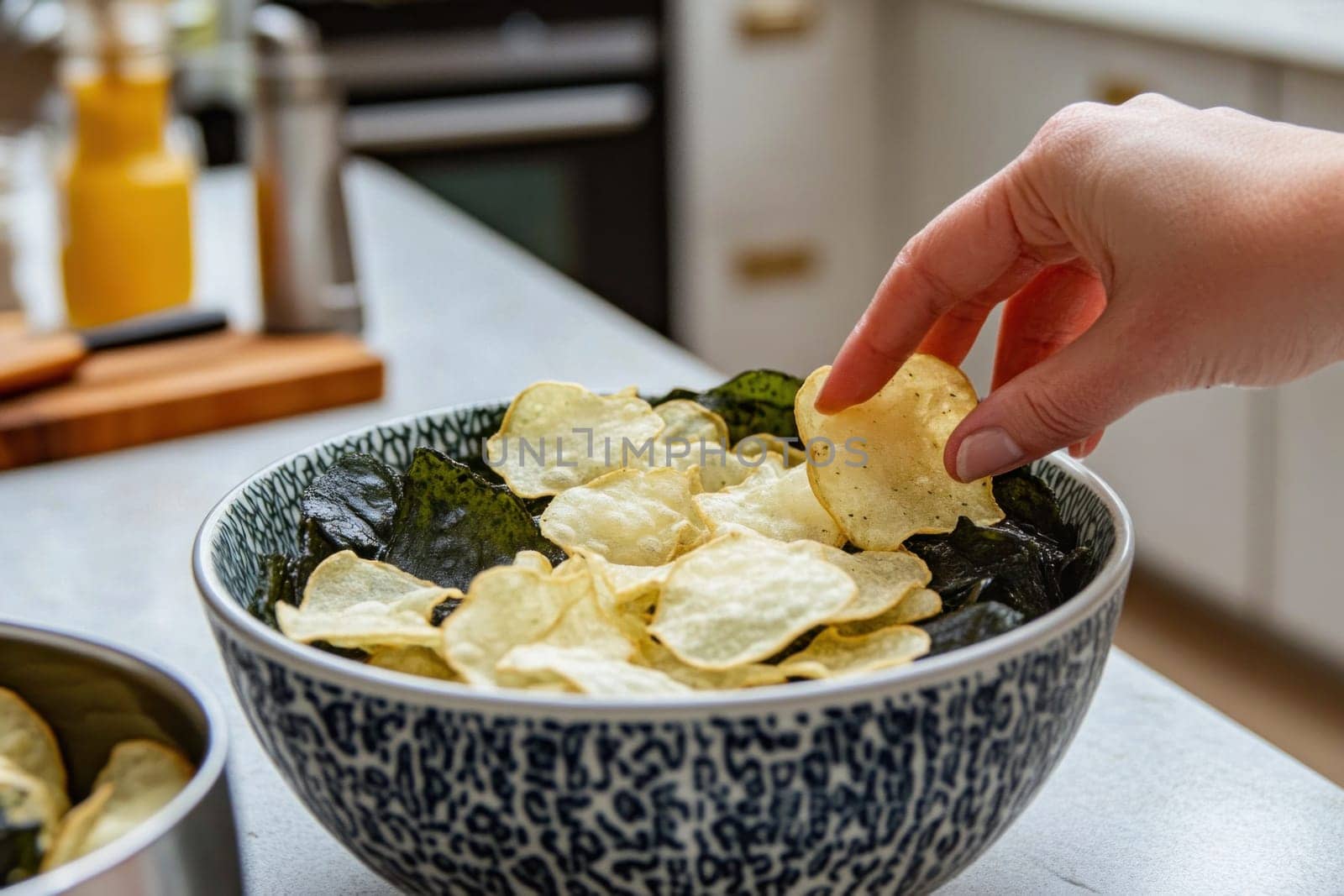 Woman grabbing a delicious cassava chips with nori seaweed in a bowl in a modern kitchen