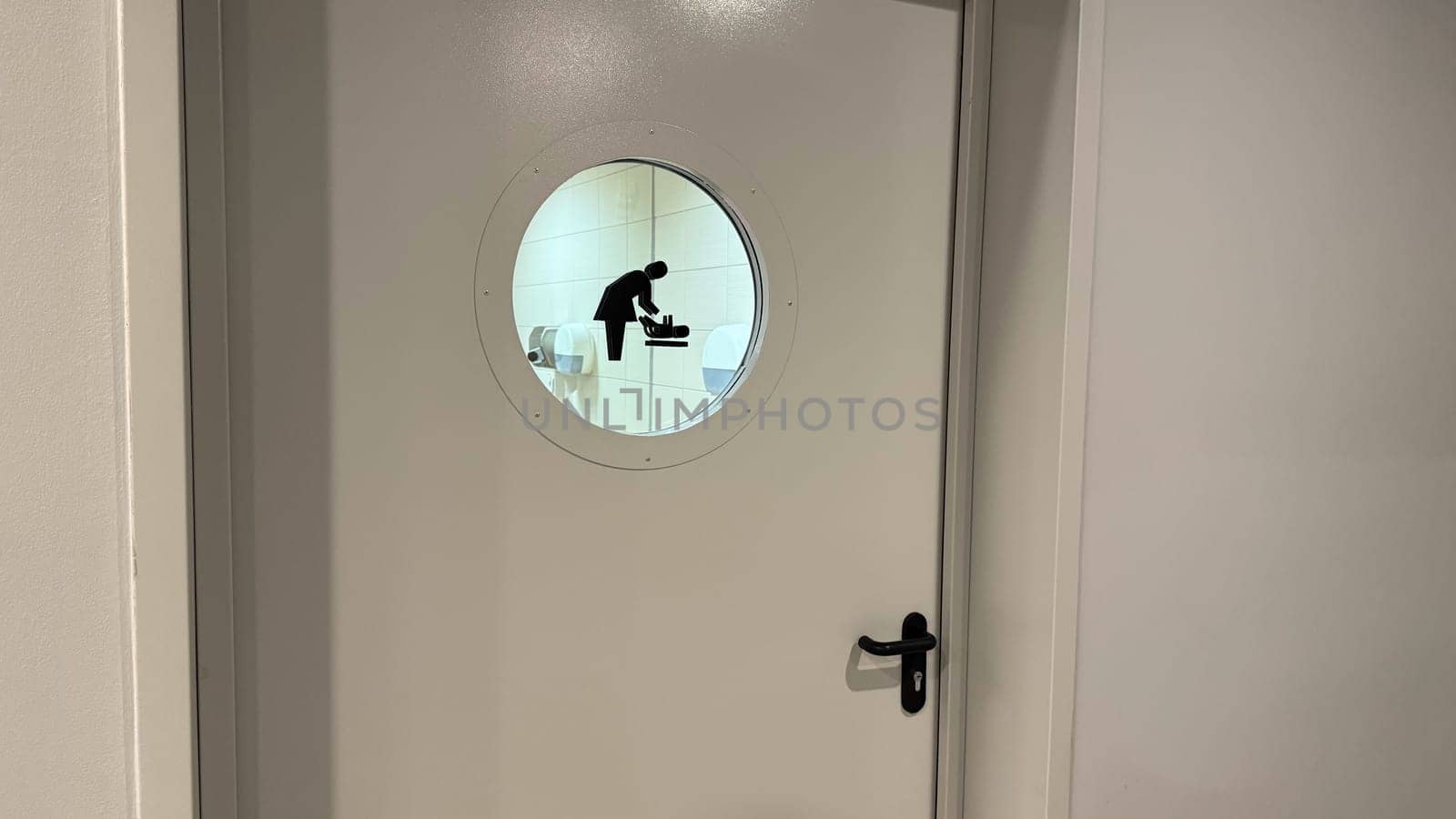 Door to baby changing room with symbol on glass window in public place, comfortable space with care for mothers with small children, entrance to room for changing baby diaper