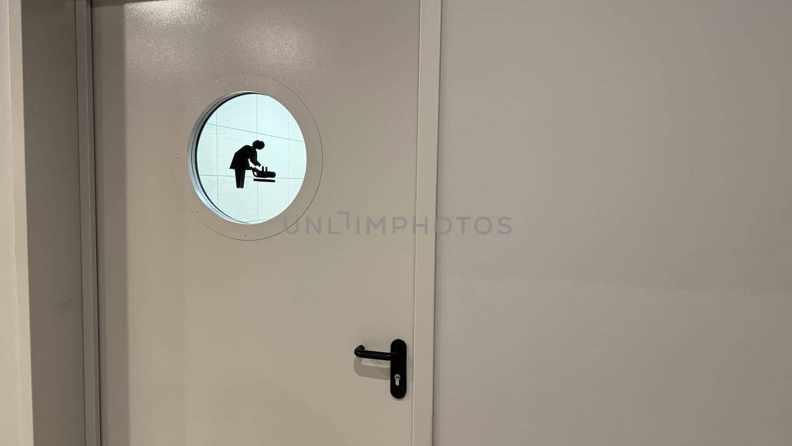 Entrance door to room for caring for small child. Door to public toilet for changing baby diaper with mother and baby sign