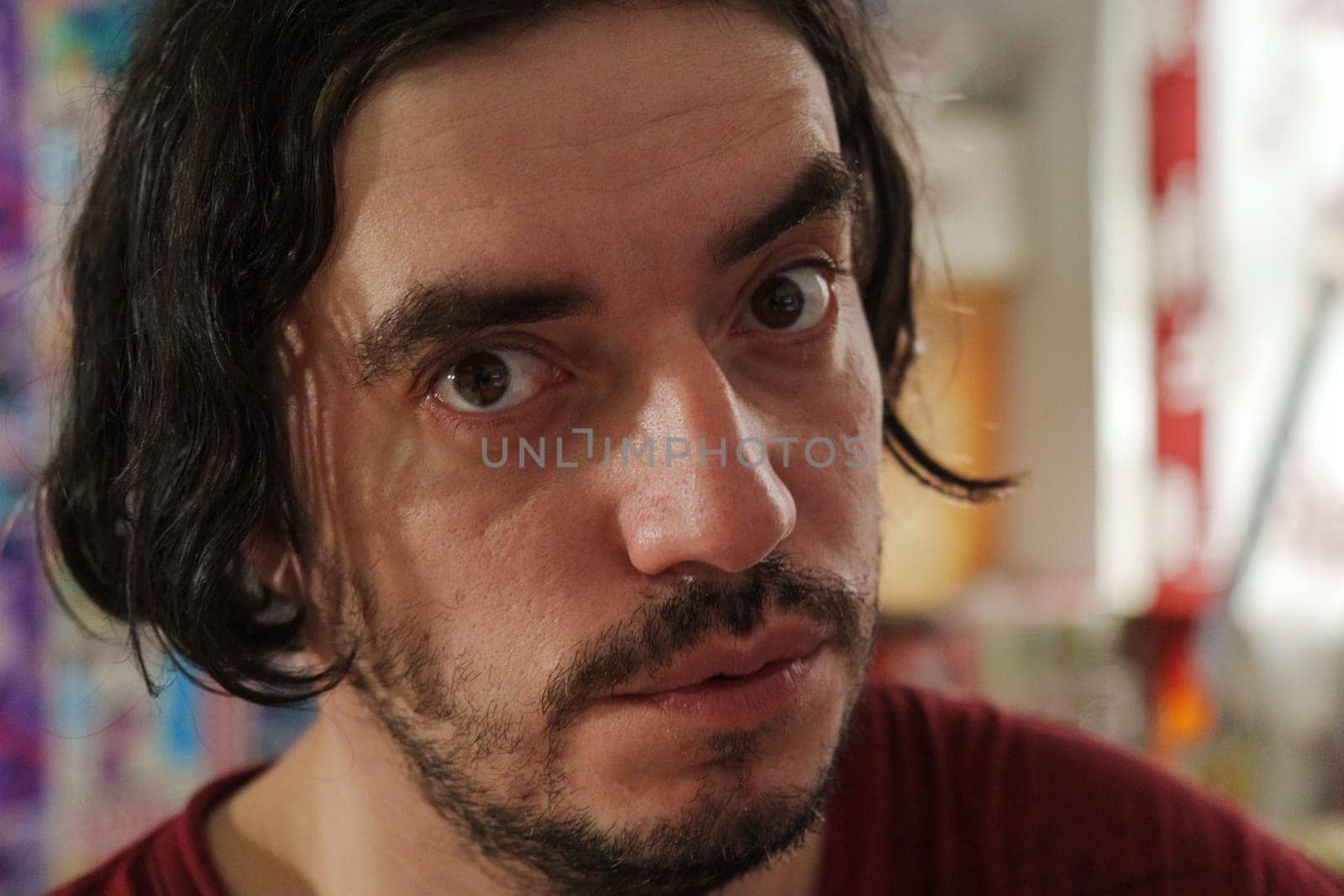 A candid moment of a smiling man with long hair in a vibrant indoor setting showcasing lively colors and interesting decor