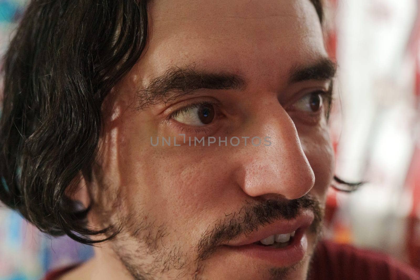 A contemplative moment captured in an artistic environment featuring a man with expressive features and wavy hair at an intimate gathering