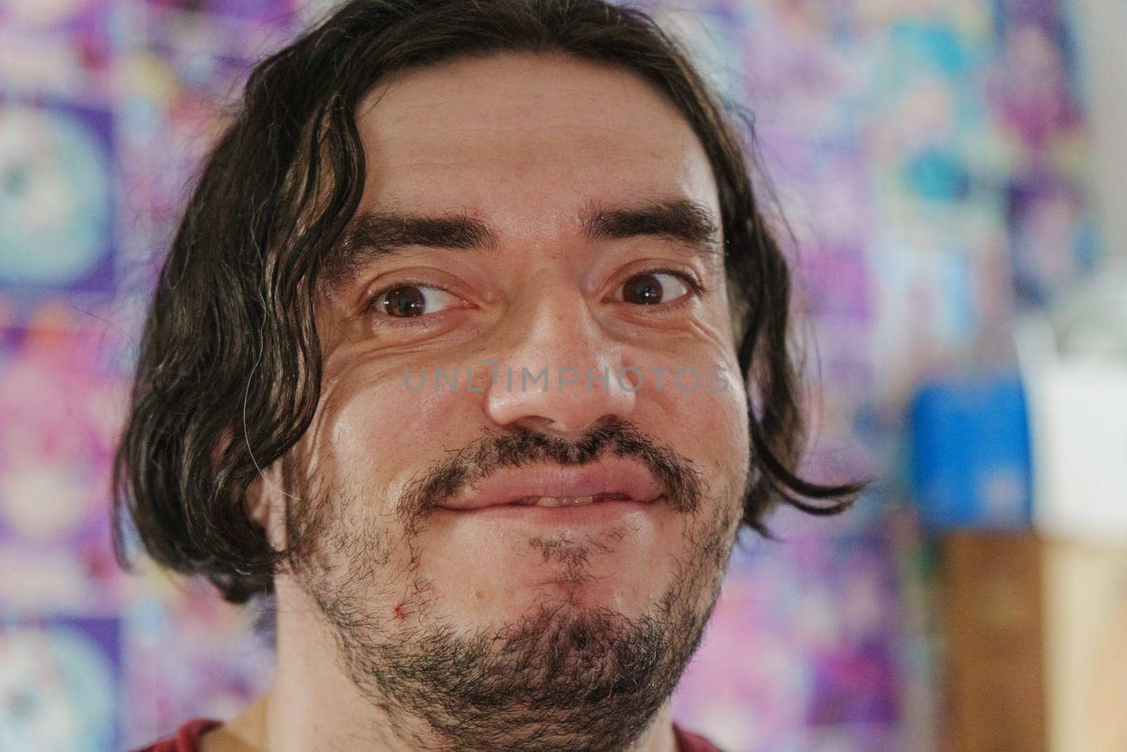 An individual with a friendly expression showcases warmth and enthusiasm, surrounded by colorful artwork