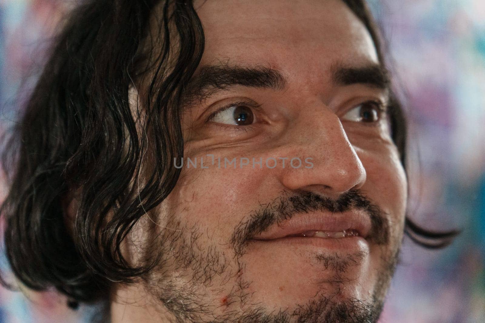 An individual with a friendly expression showcases warmth and enthusiasm, surrounded by colorful artwork