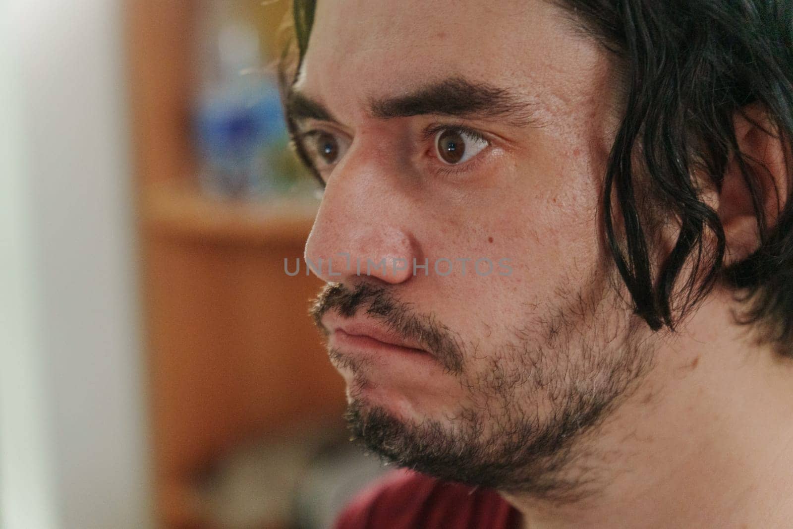The man gazes with interest, his tousled hair framing a thoughtful face.