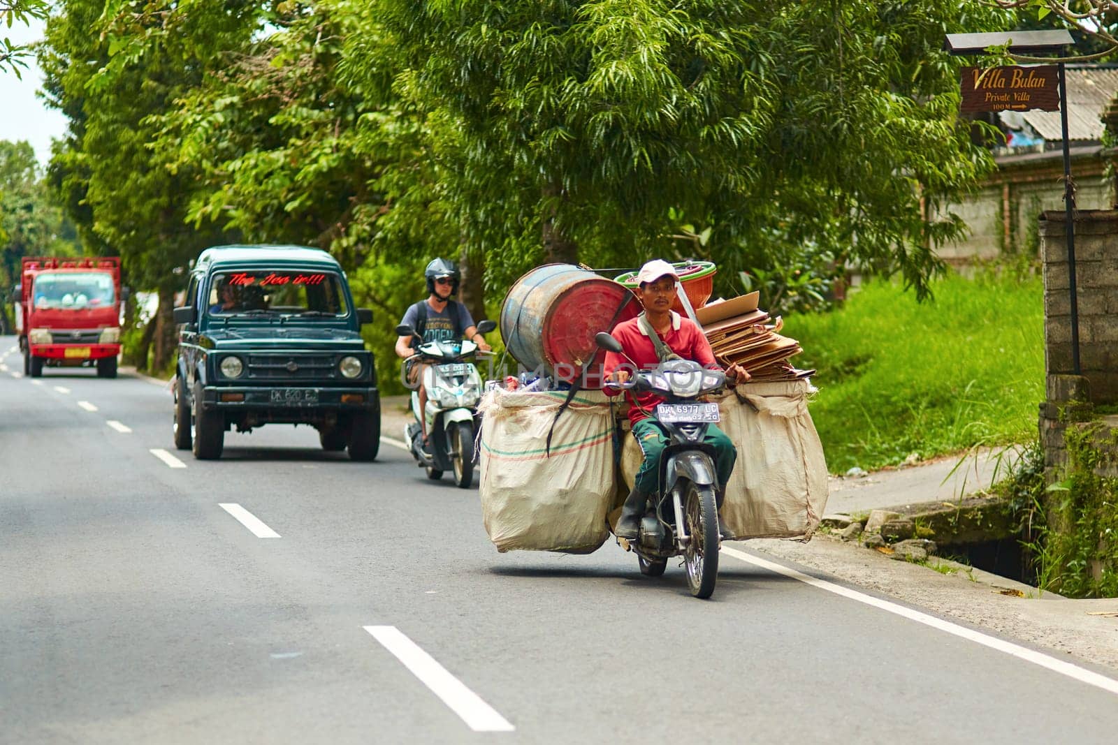 A person on a motorcycle rides a scenic asphalt road in Asia. Bali, Indonesia - 01.03.2018