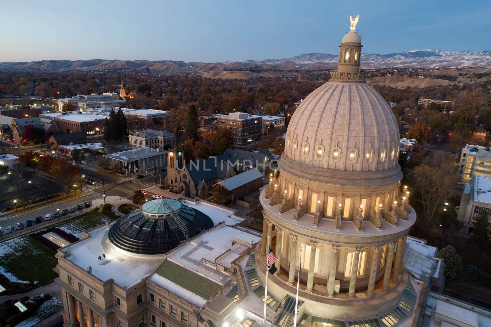 A large dome building with a flag on top. The dome is lit up at night. The building is in a city