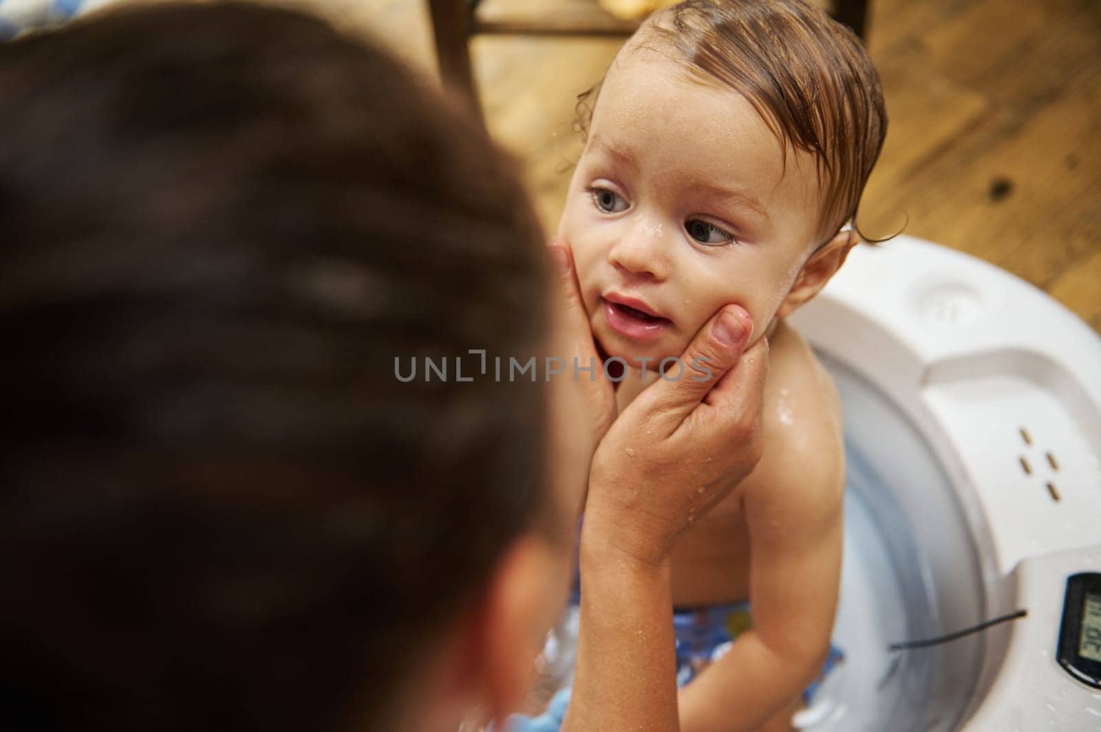 A tender moment of a mother bathing her baby in a tub, wrapped in love and care. The warm home environment and gentle touch evoke feelings of comfort, safety, and affection.