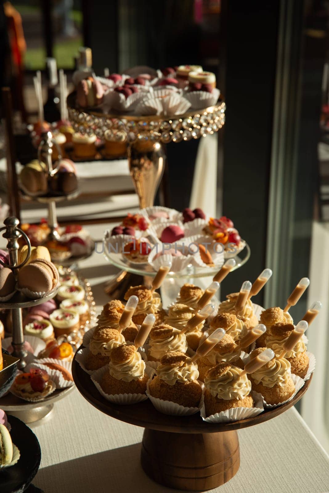 A table with a variety of desserts and pastries. The desserts are arranged in glass bowls and trays.