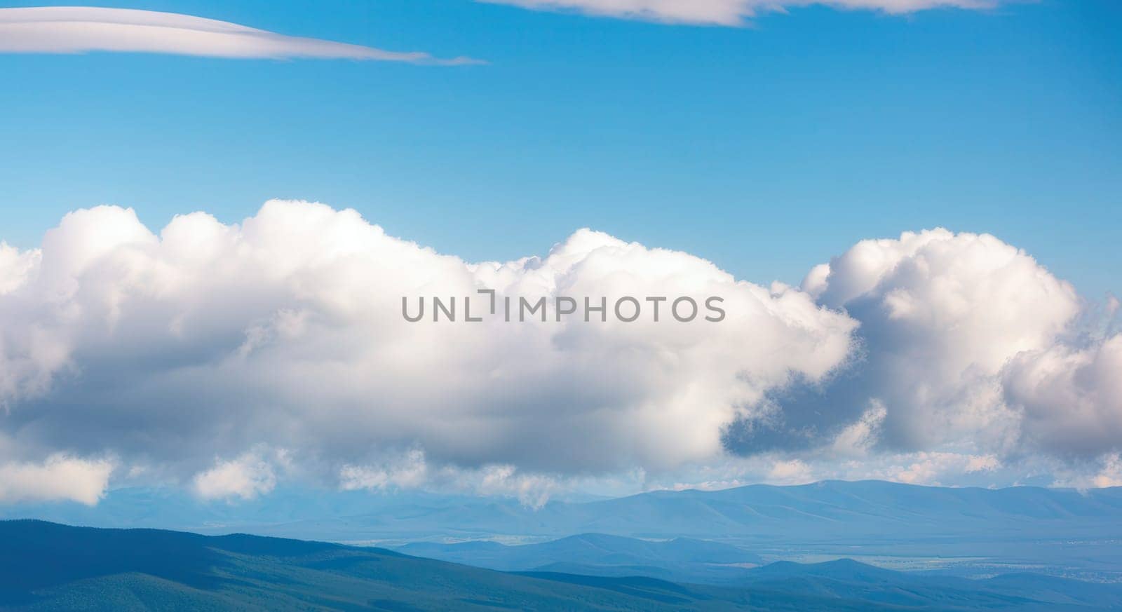 Expansive blue sky and fluffy white clouds drift above serene mountain ranges, creating a tranquil scene ideal for nature-themed designs. the contrast between the sky and the mountainous terrain emphasizes the beauty of untouched landscapes.