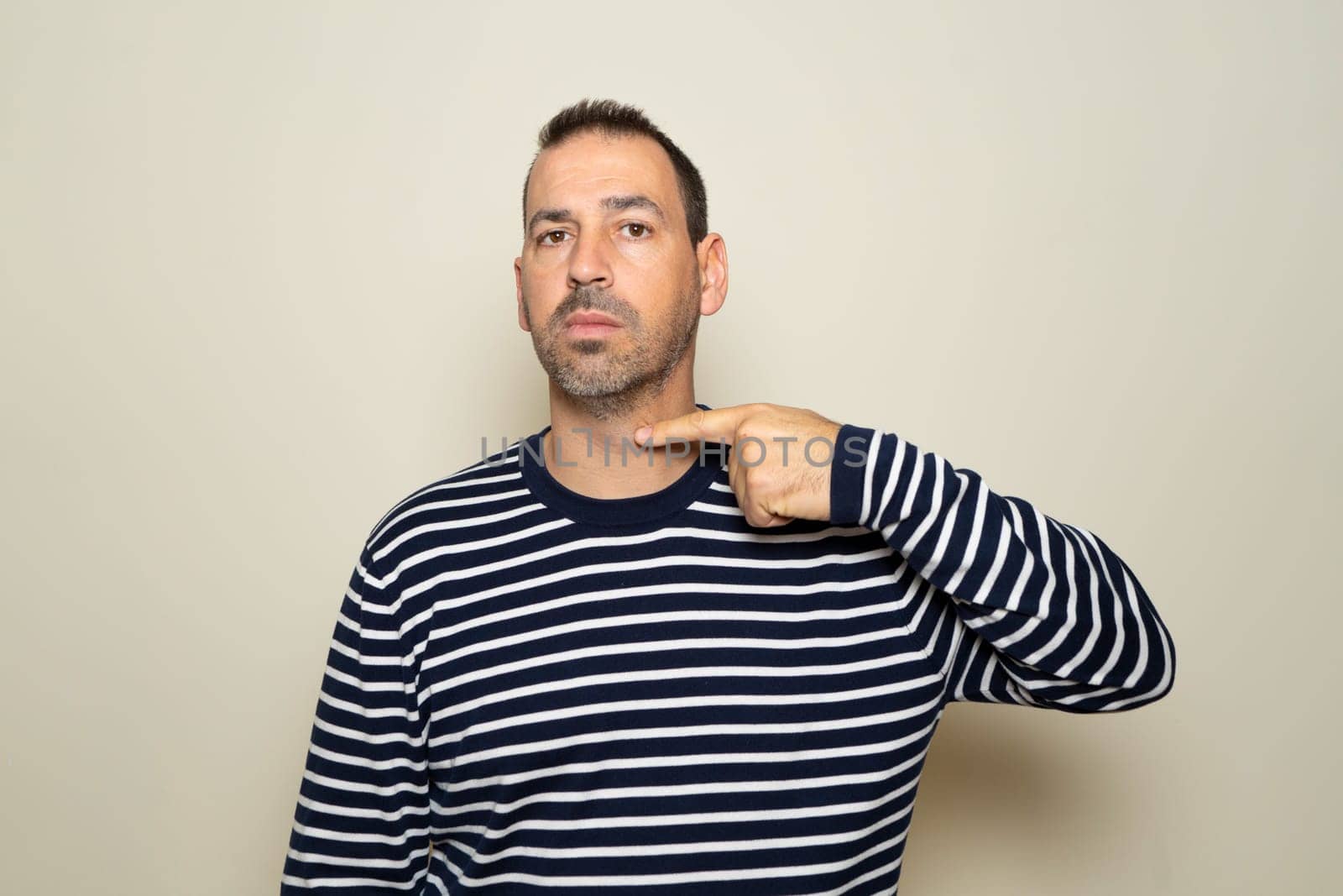 A bearded Hispanic man threatens to cut his throat. The man has a violent look and makes threatening gestures. The man threatens and looks for a fight
