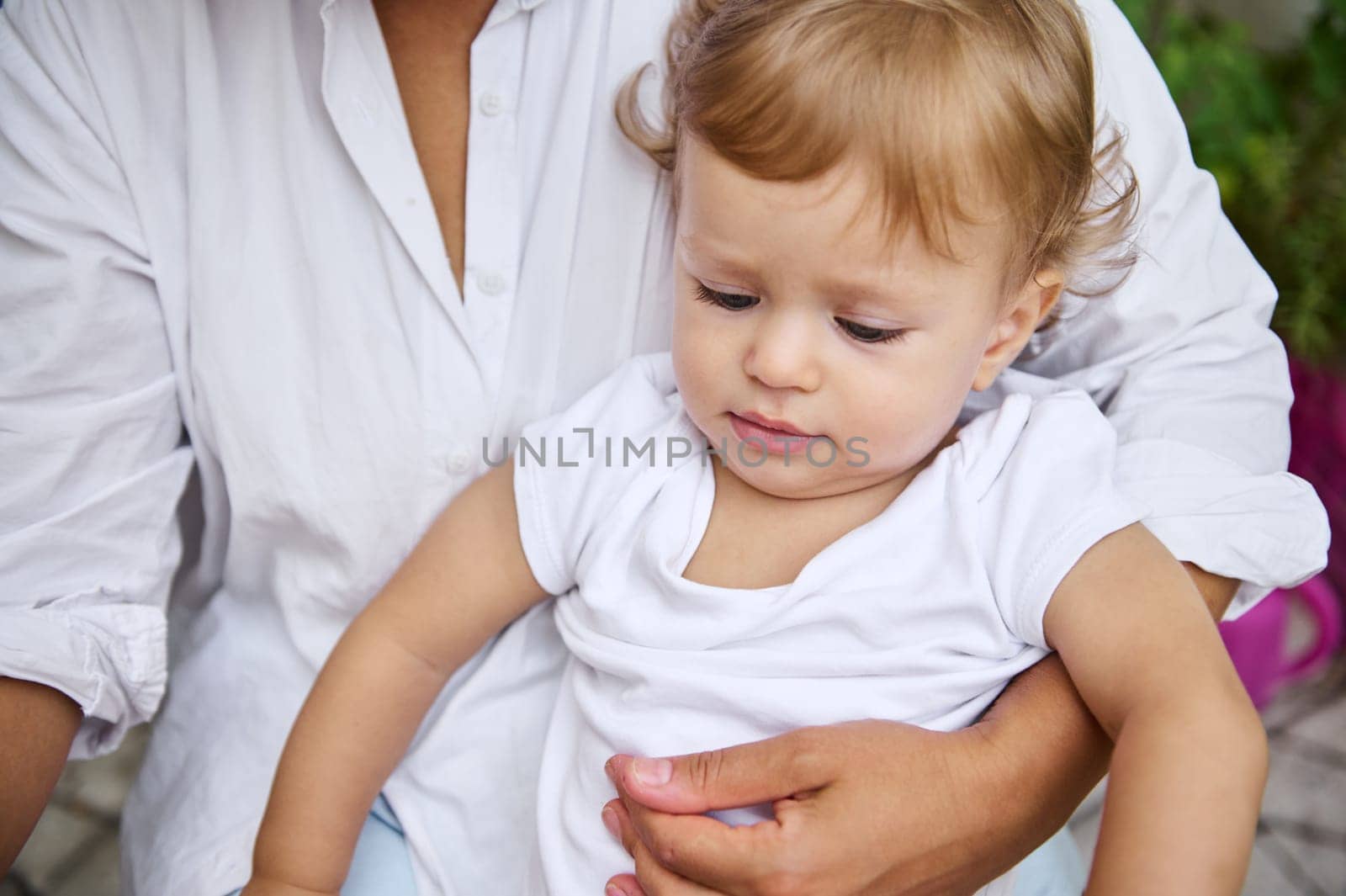 A nurturing moment captured as a mother lovingly holds her baby boy. The scene exudes warmth and tenderness, highlighting the bond between parent and child in an outdoor setting.