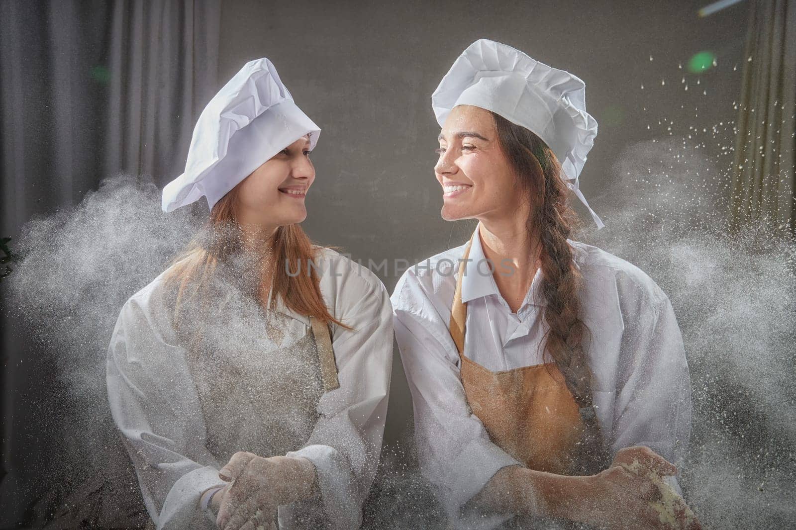 Two friends enjoy a playful moment in the kitchen, surrounded by flour, showcasing their love for cooking and friendship.