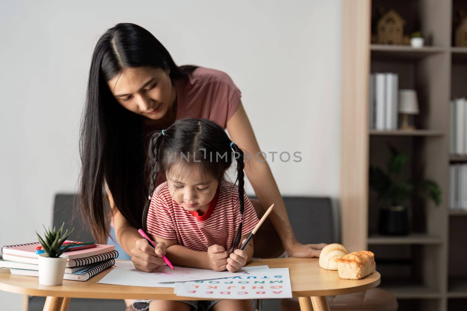 A mother and daughter enjoying a creative learning session at home, surrounded by art supplies and books.
