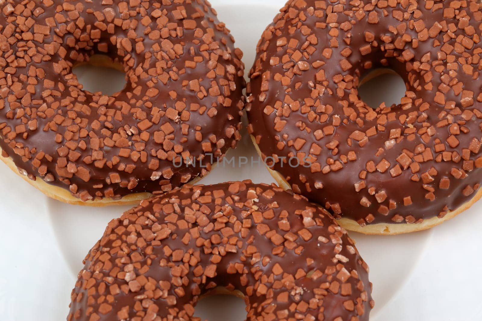 Indulge in a tempting trio of luscious chocolatecovered donuts, beautifully topped with vibrant and crunchy sprinkles