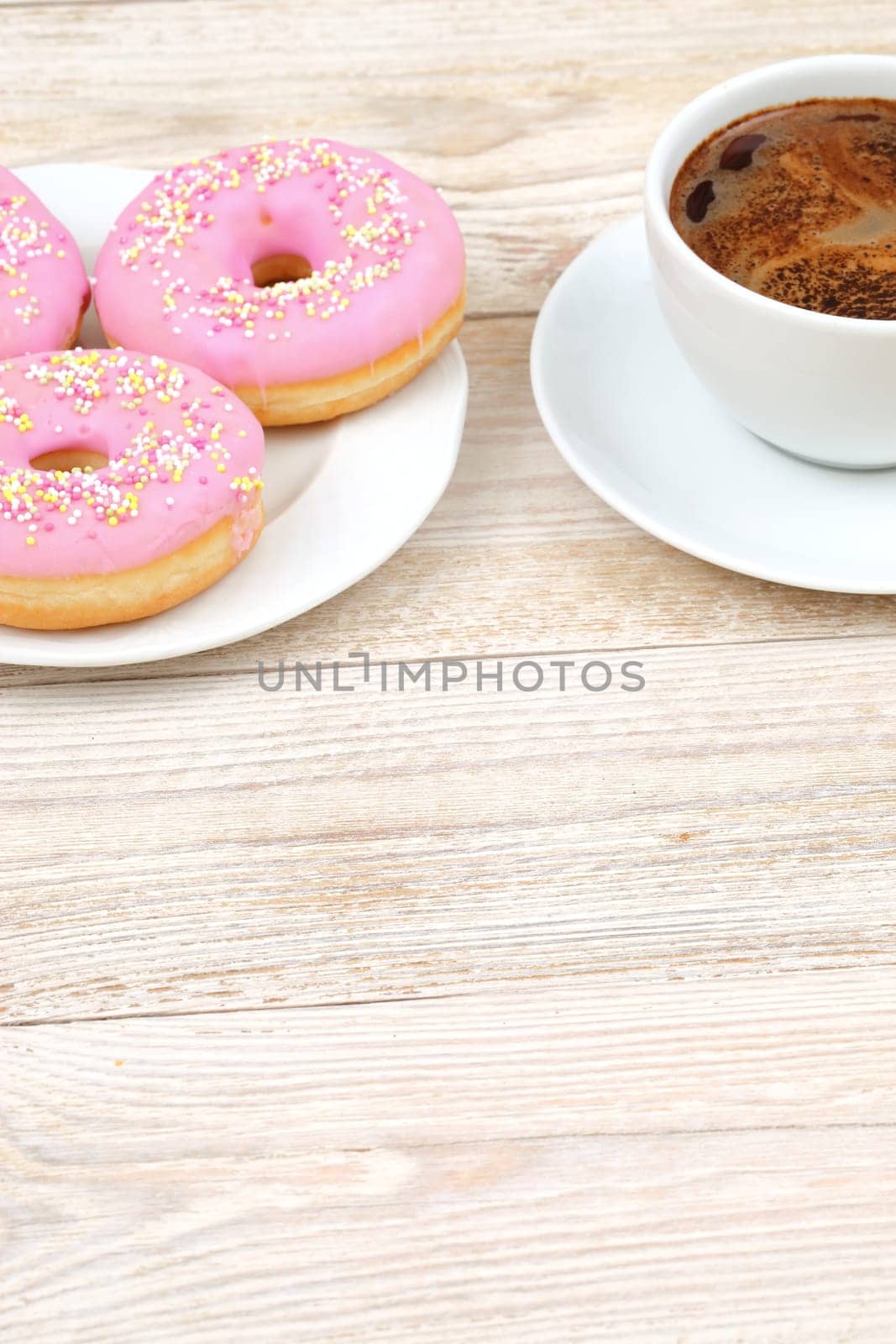 Deliciously sweet pink donuts perfectly paired with a warm cup of coffee, ideal for breakfast or a delightful snack