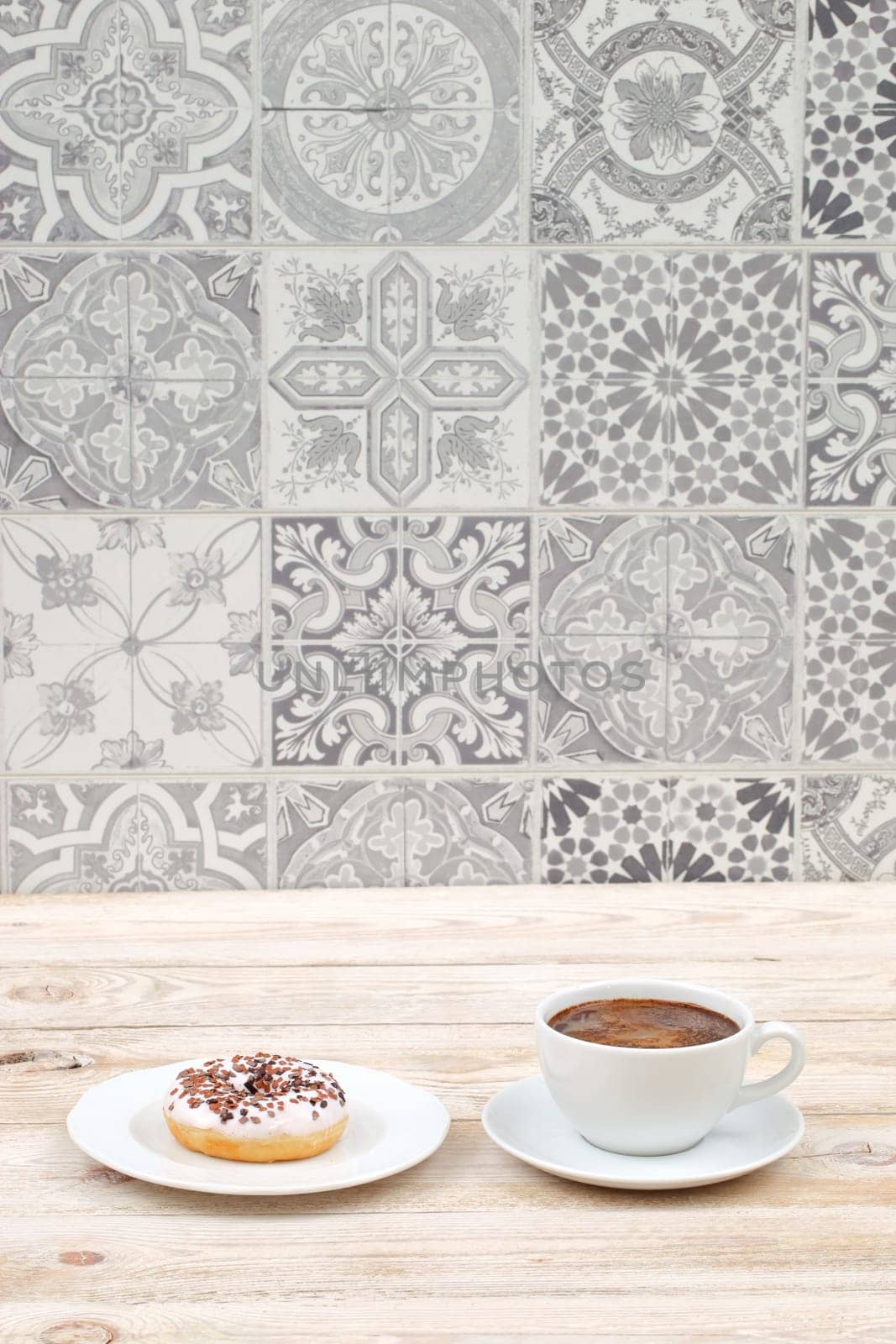 Enjoy a cozy breakfast with a steaming cup of coffee and a delicious donut against a stylish tile backdrop