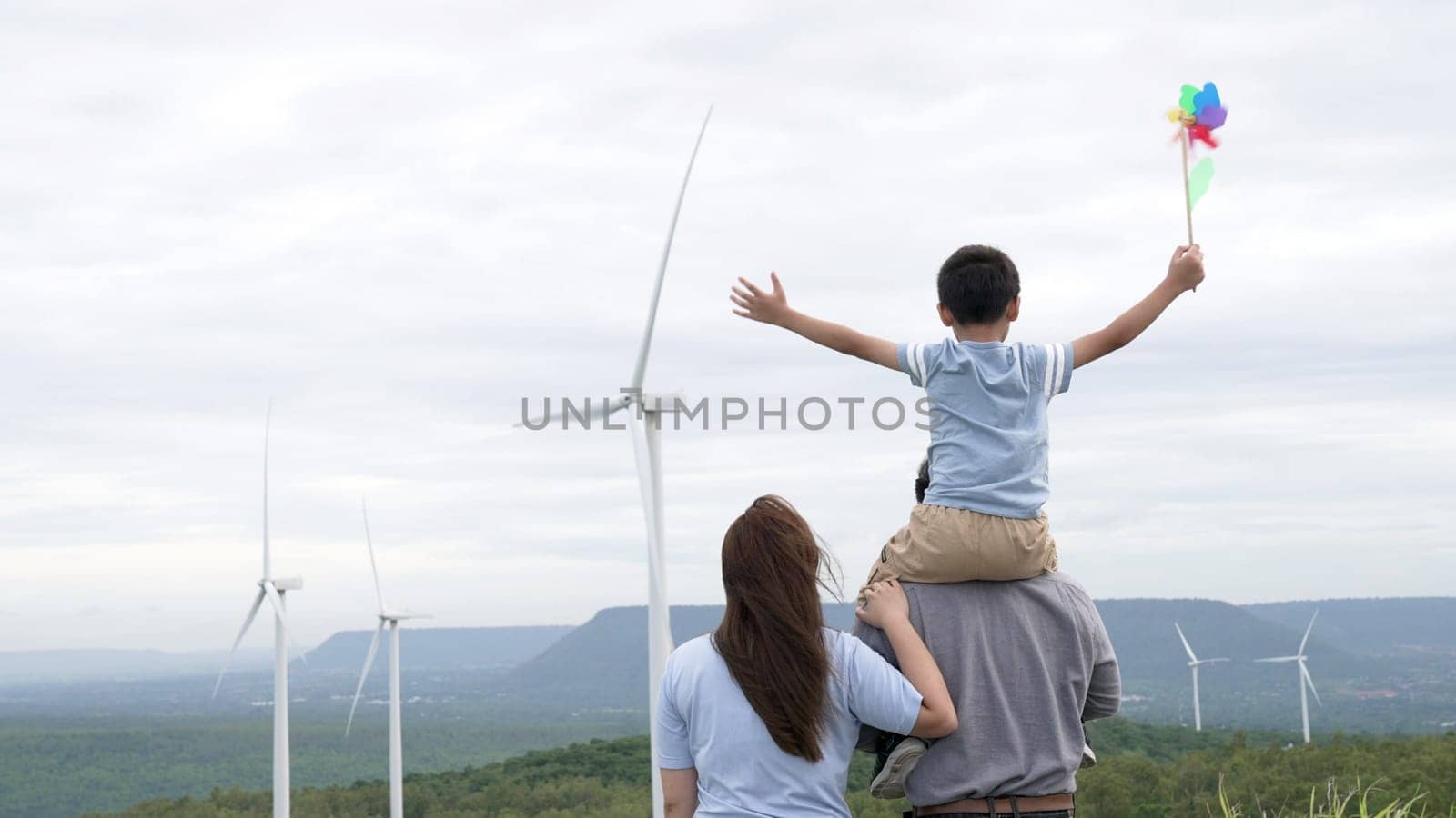 Concept of progressive happy family enjoying their time at the wind turbine farm by biancoblue