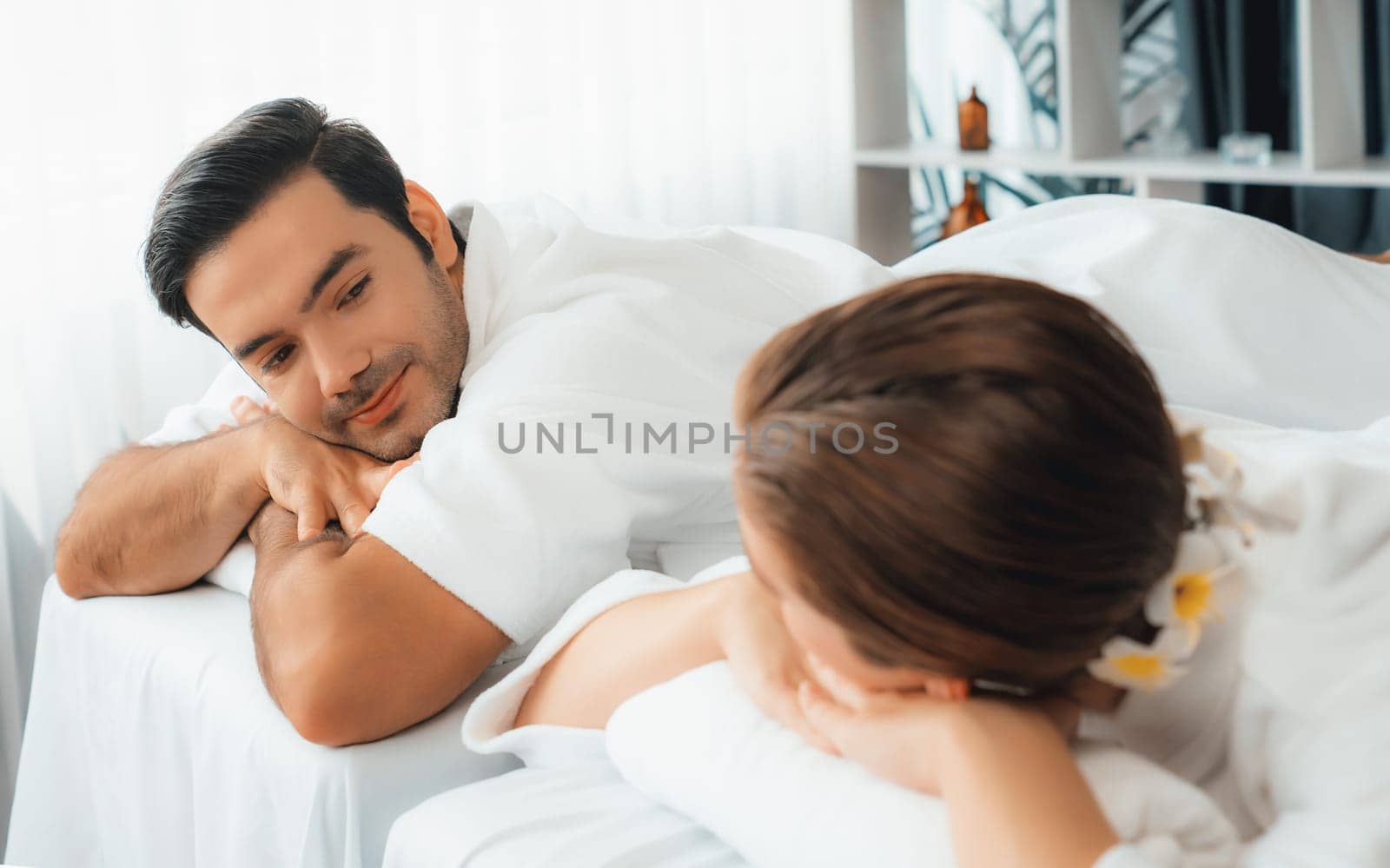 Caucasian couple customer enjoying relaxing anti-stress spa massage and pampering with beauty skin recreation leisure in day light ambient salon spa at luxury resort or hotel. Quiescent