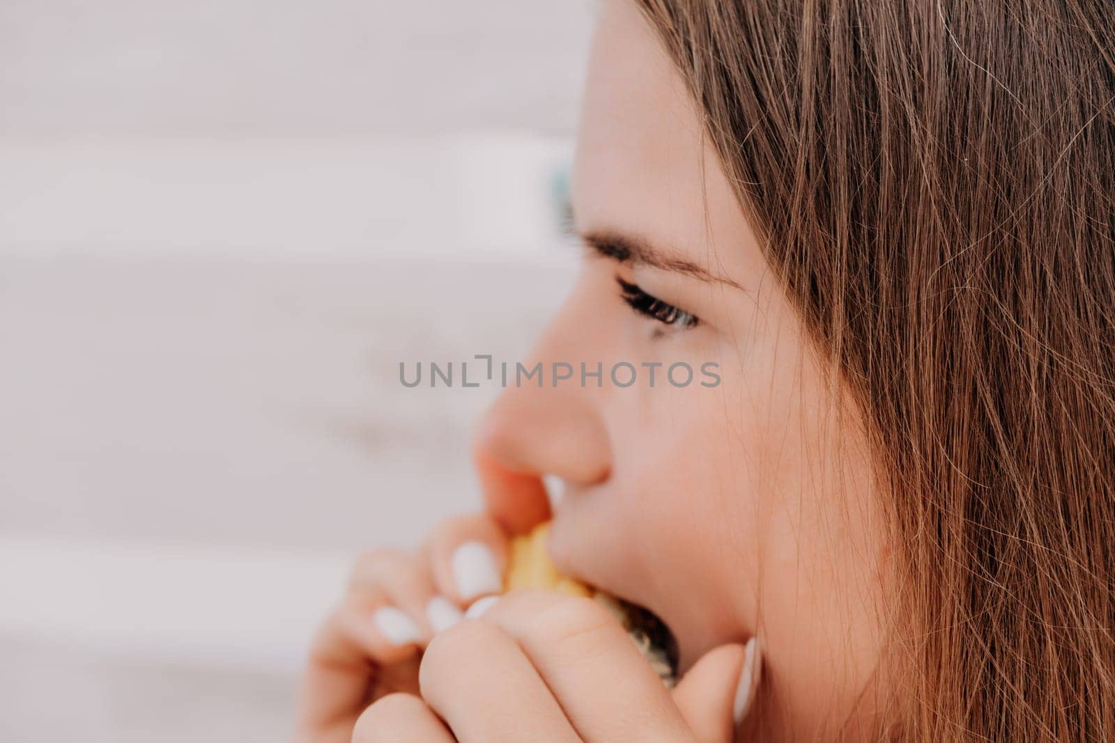 Woman eats corn on beach. Vegetarian hipster woman eat fresh organic grilled corn. Happy lady on sea beach sunset or ocean sunrise. Travel, explore, active yoga and meditation lifestyle concept. by panophotograph