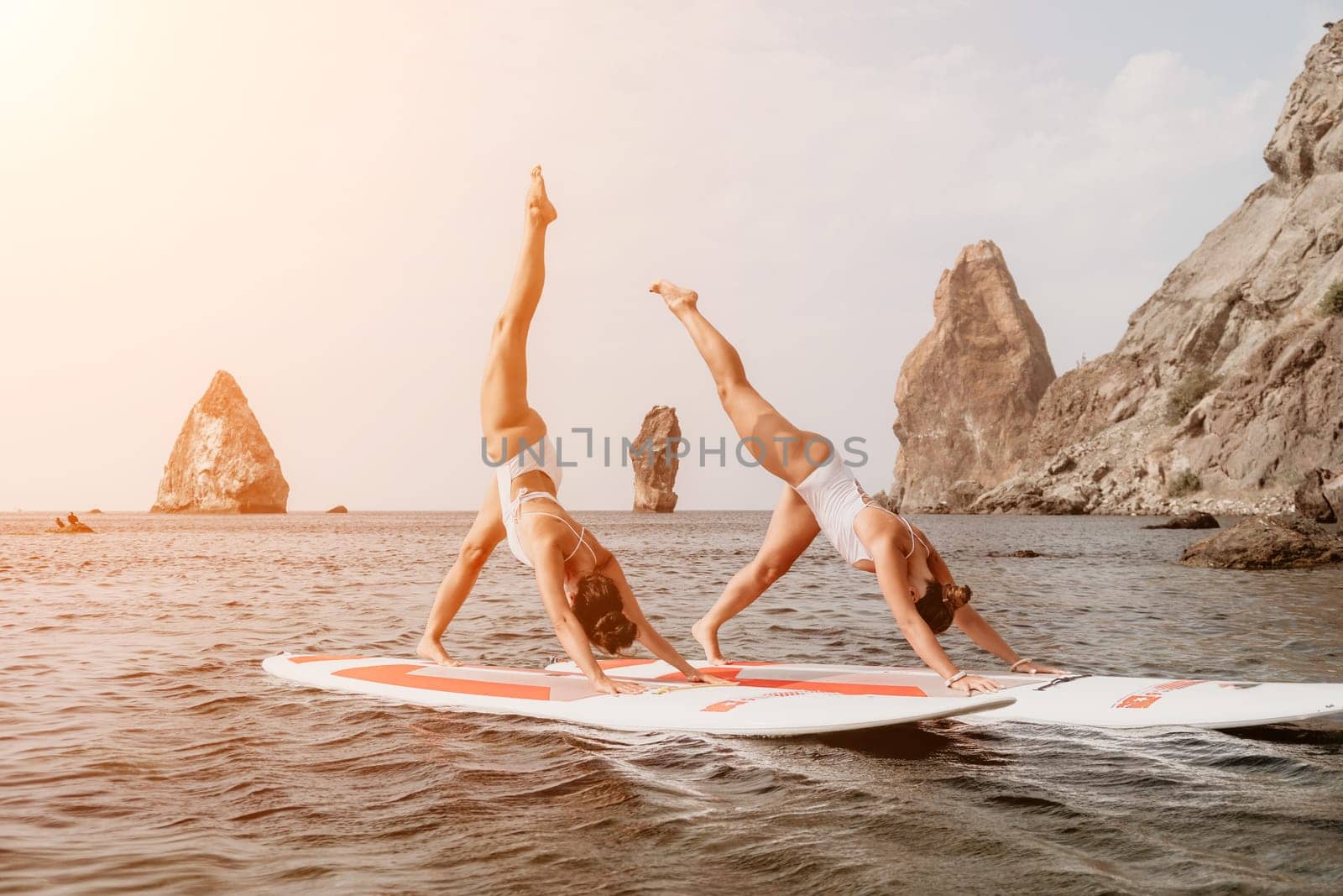 Woman sup yoga. Middle age sporty woman practising yoga pilates on paddle sup surfboard. Female stretching doing workout on sea water. Modern individual hipster outdoor summer sport activity