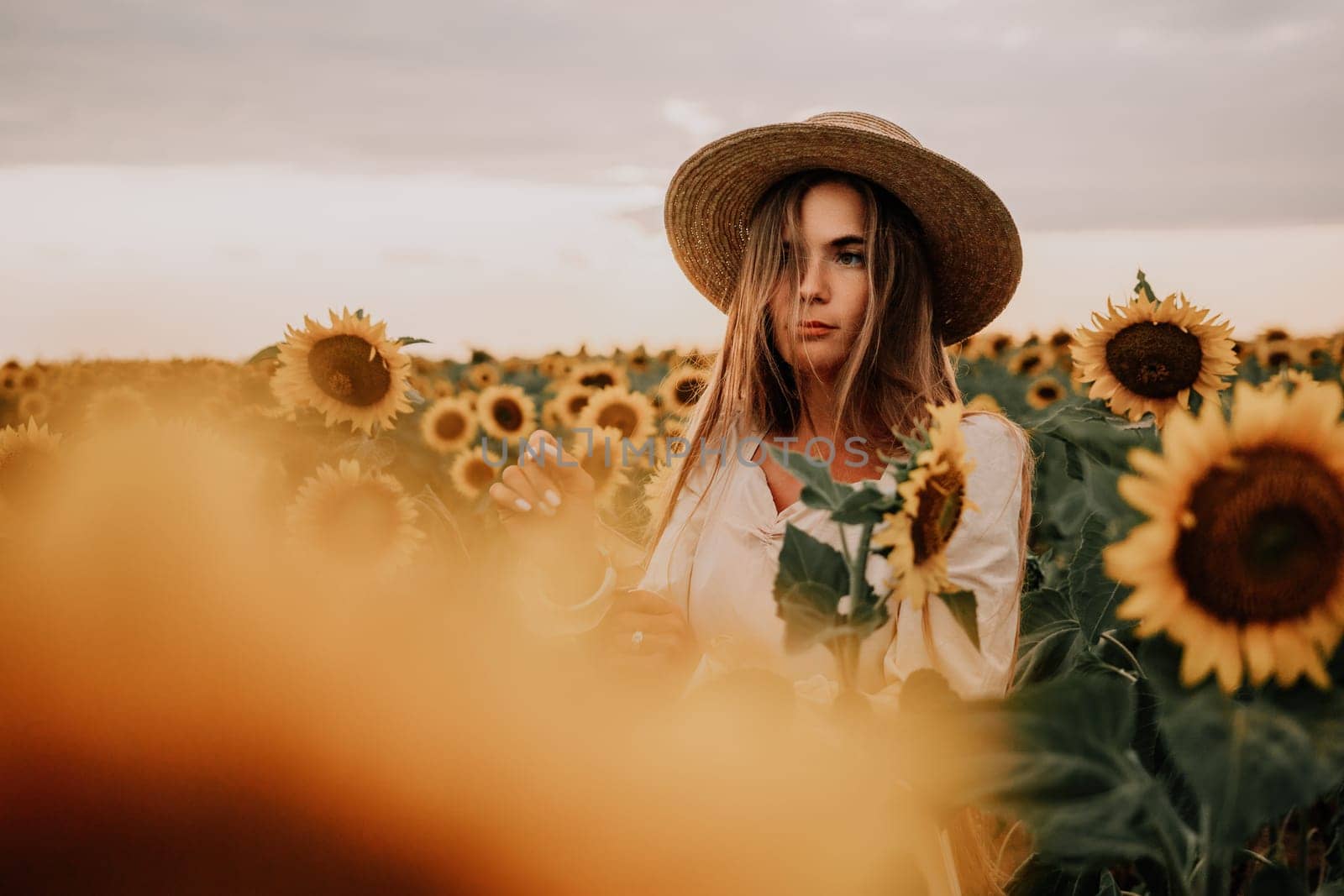 Woman in the sunflowers field. Summer time. Young beautiful woman standing in sunflower field.