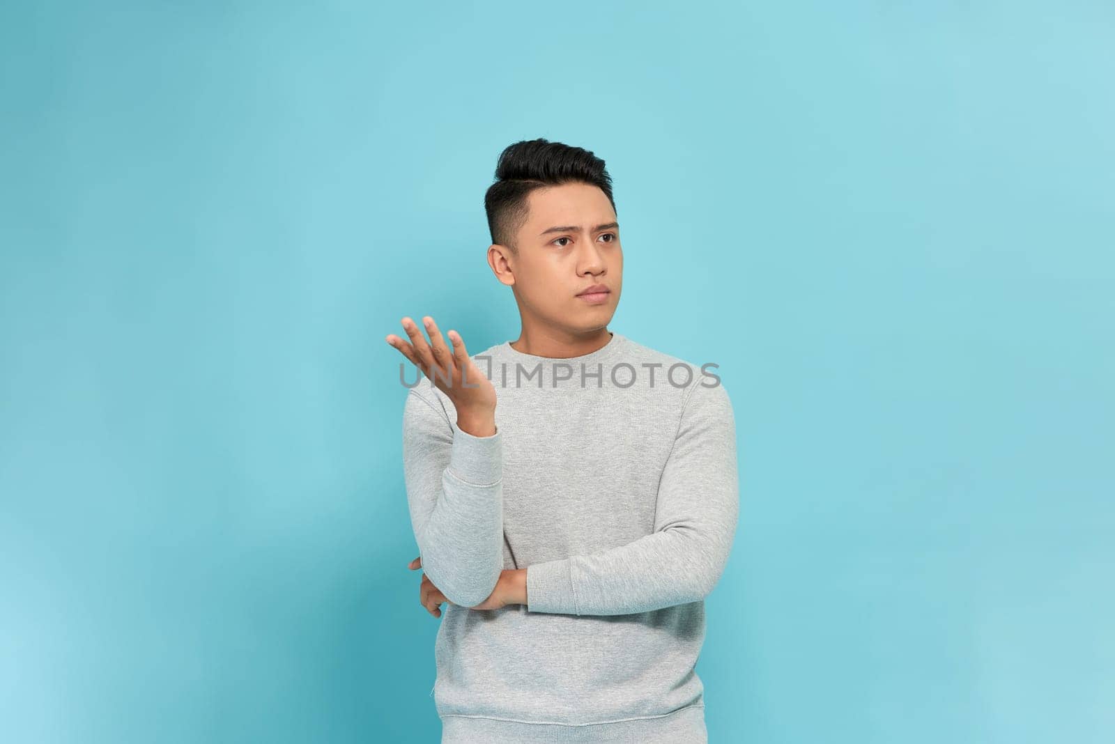 Young asian man explains to someone isolated on blue background